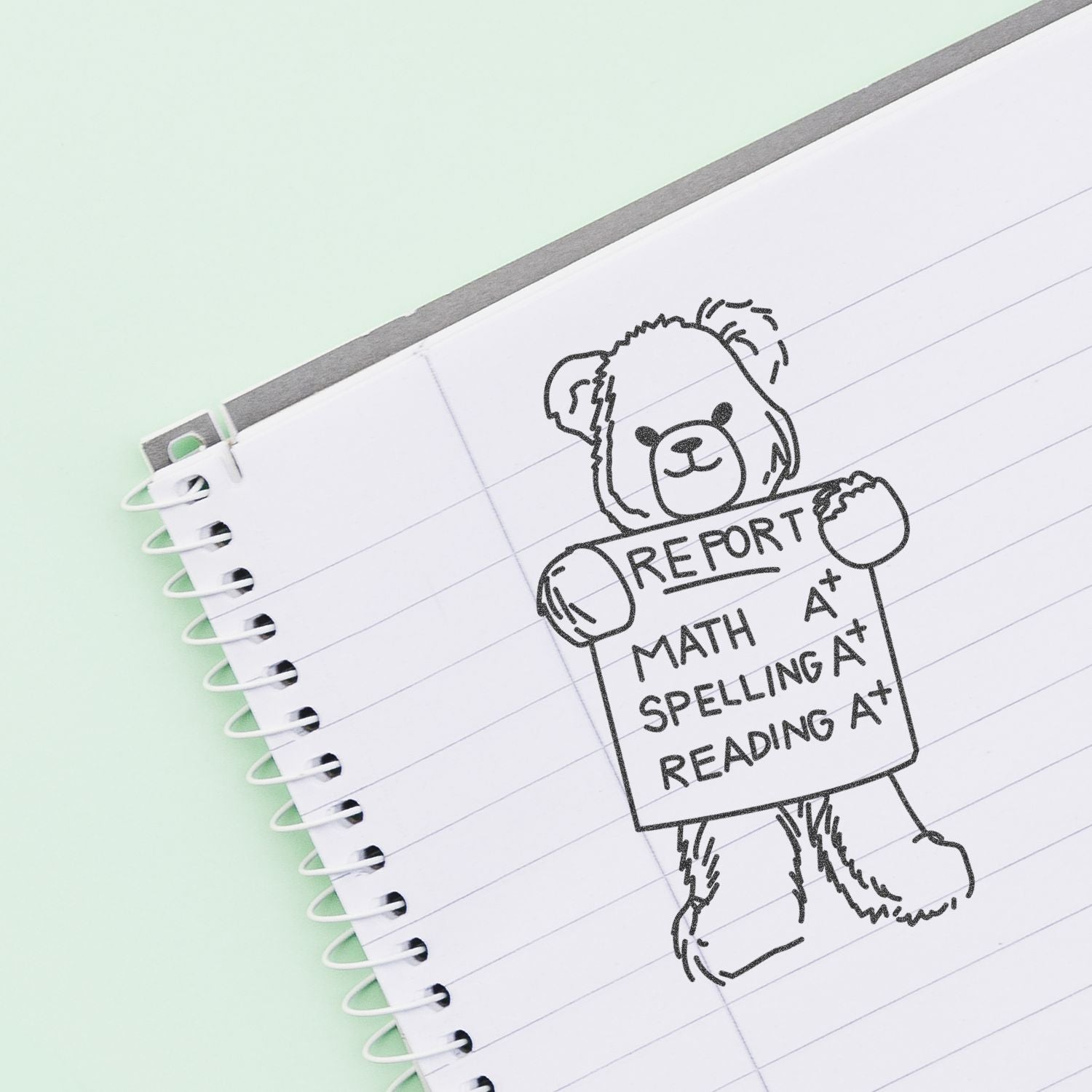 Cute bear doodle on a spiral notebook holding a report card with A+ grades in math, spelling, and reading.