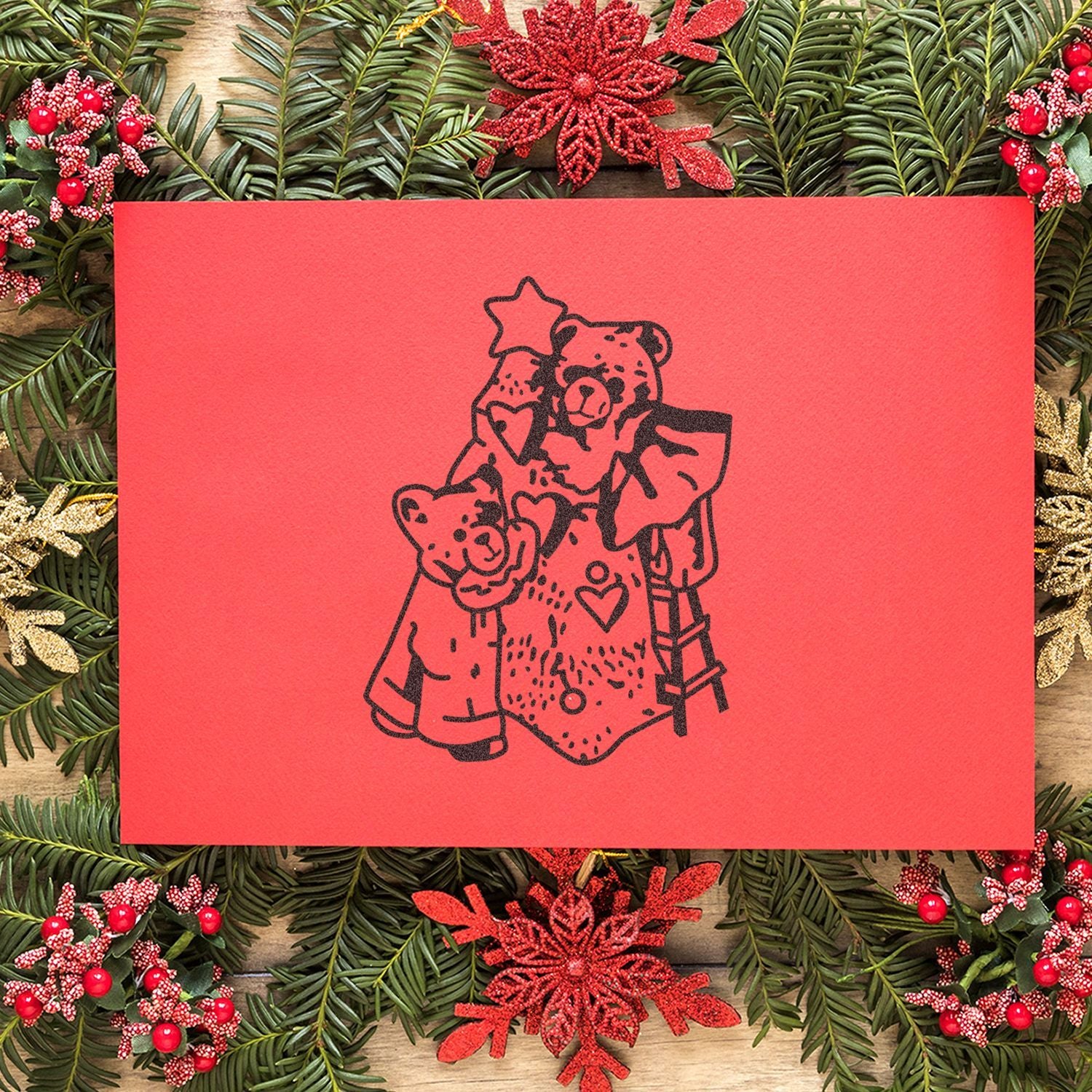 Red Christmas greeting card with teddy bear illustration surrounded by festive pine greenery and red holiday decorations.