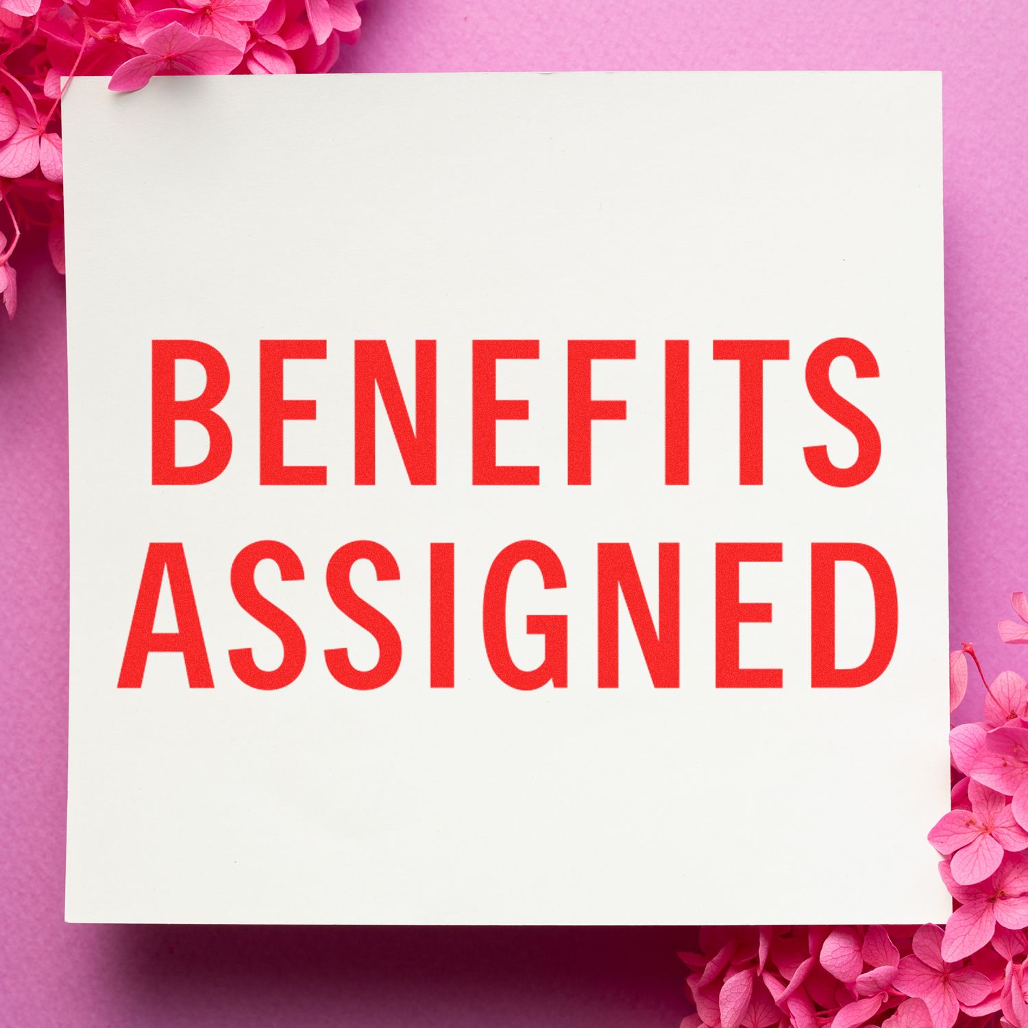 Benefits Assigned text on a white card with pink flowers and purple background for a benefits announcement.