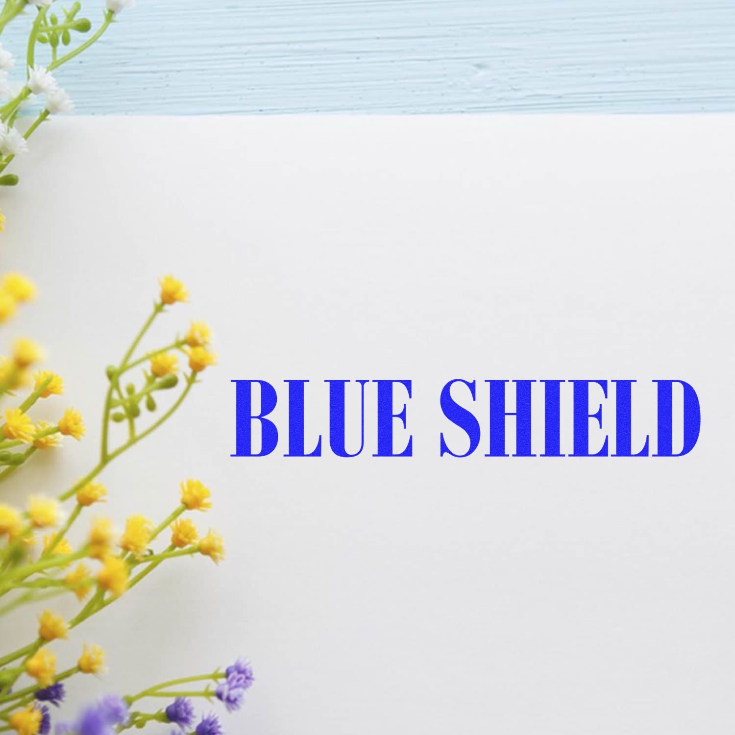 Blue Shield logo with floral border on white background and light blue wooden texture header.