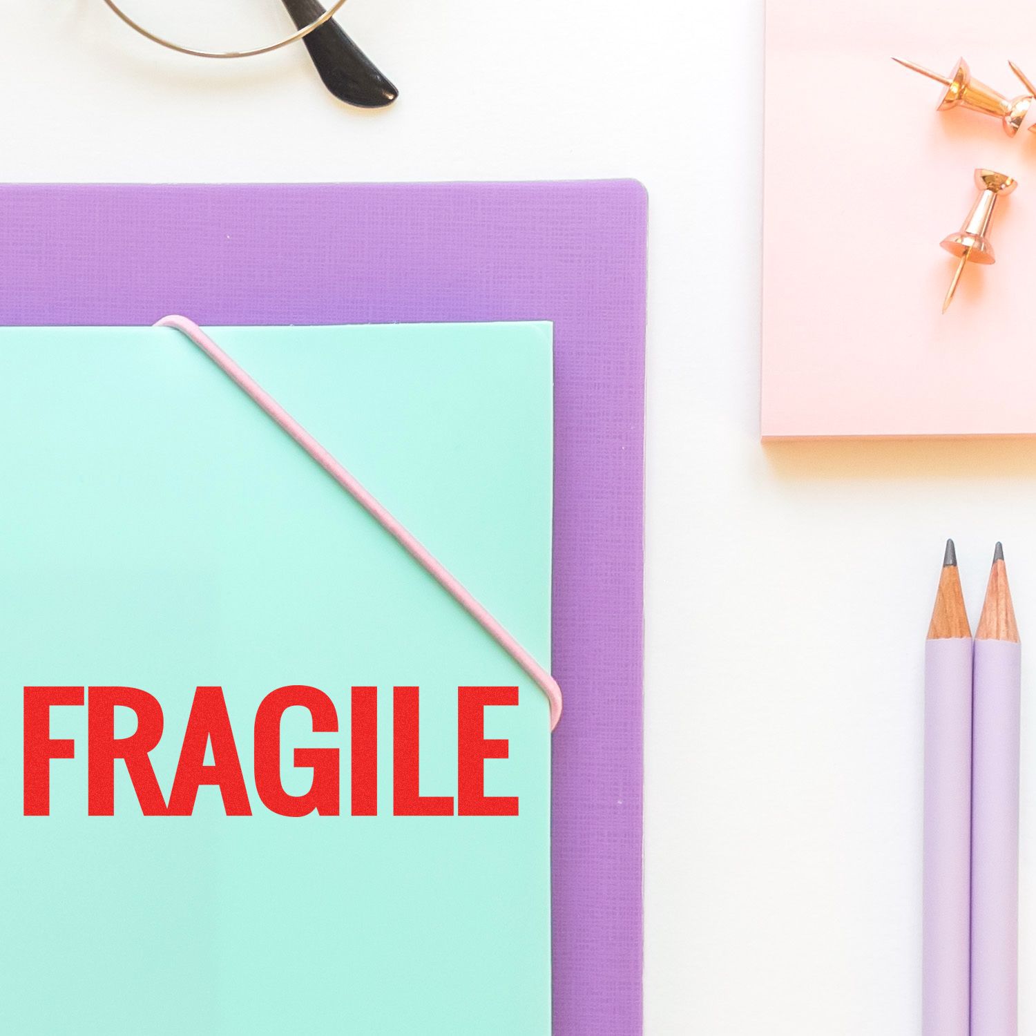 Fragile shipping label on stationery desk with notebooks, pencils, pushpinsillustrates careful handling and breakable items.