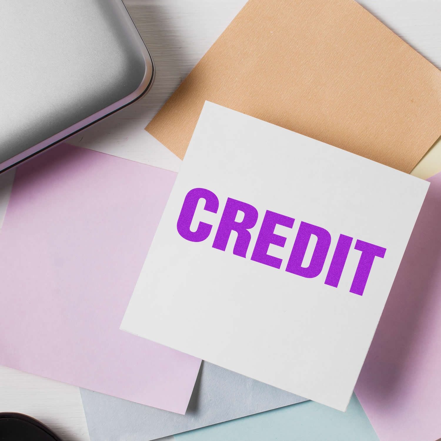 Credit concept with bold purple CREDIT text on a white card surrounded by pastel stationery and envelopes.