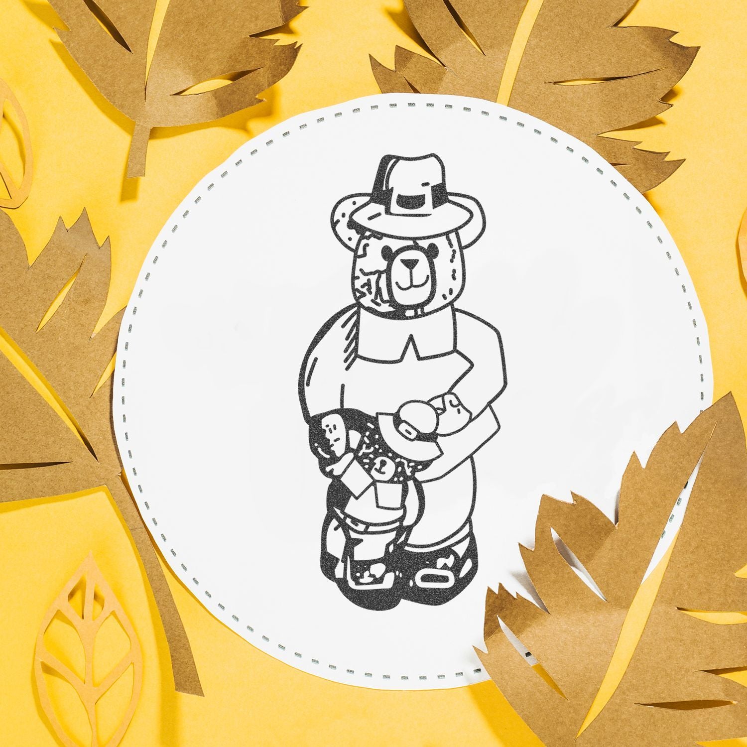 Paper craft bear illustration with autumn leaves on a yellow background.