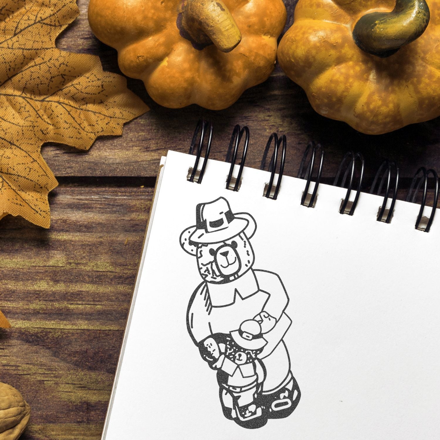 Thanksgiving autumn flat lay with pumpkin decor, fall leaves, and a spiral notebook featuring a cute teddy bear pilgrim sketch.