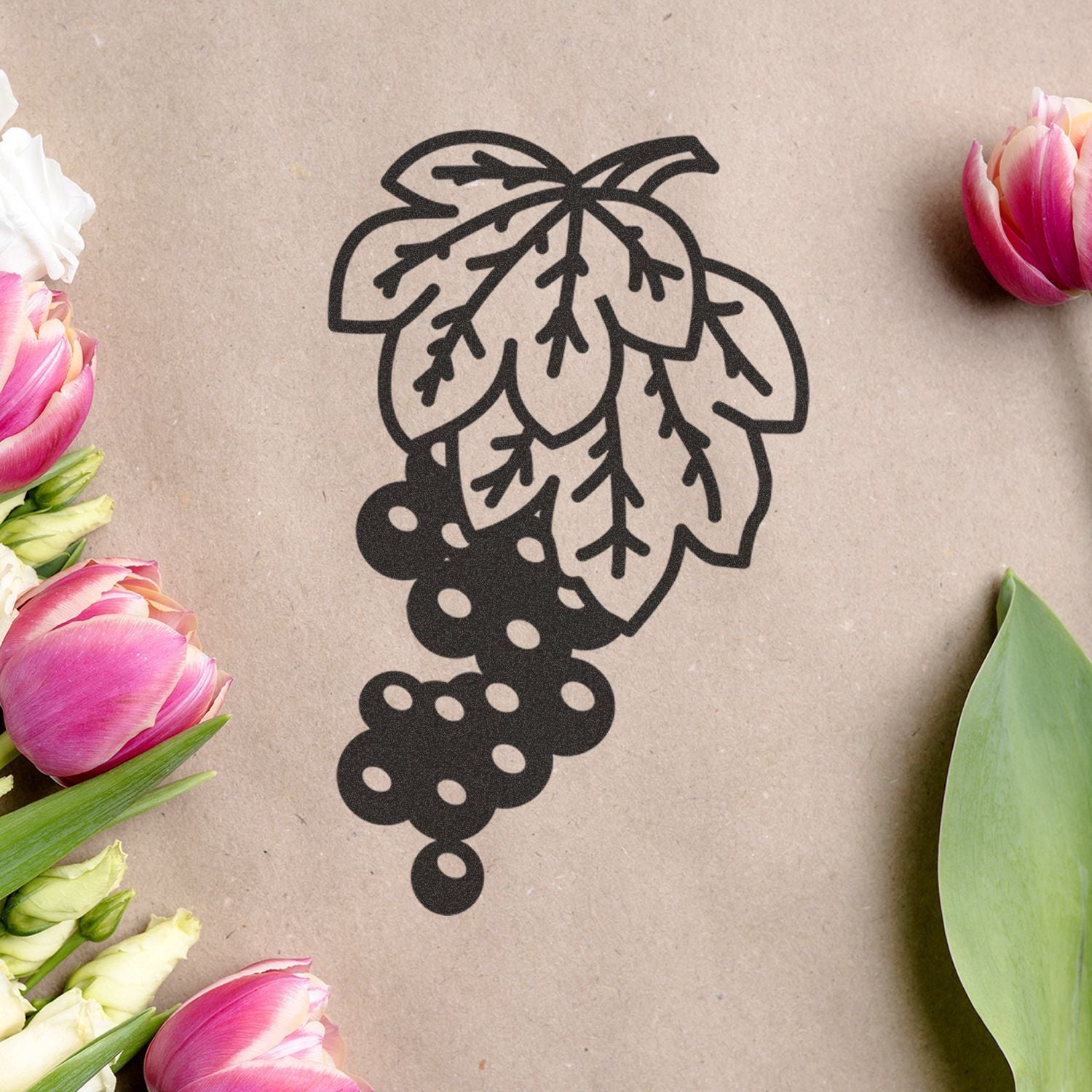 Black hop cone graphic on kraft paper background with pink tulips and floral decoration, ideal for beer brewing and botanical design.