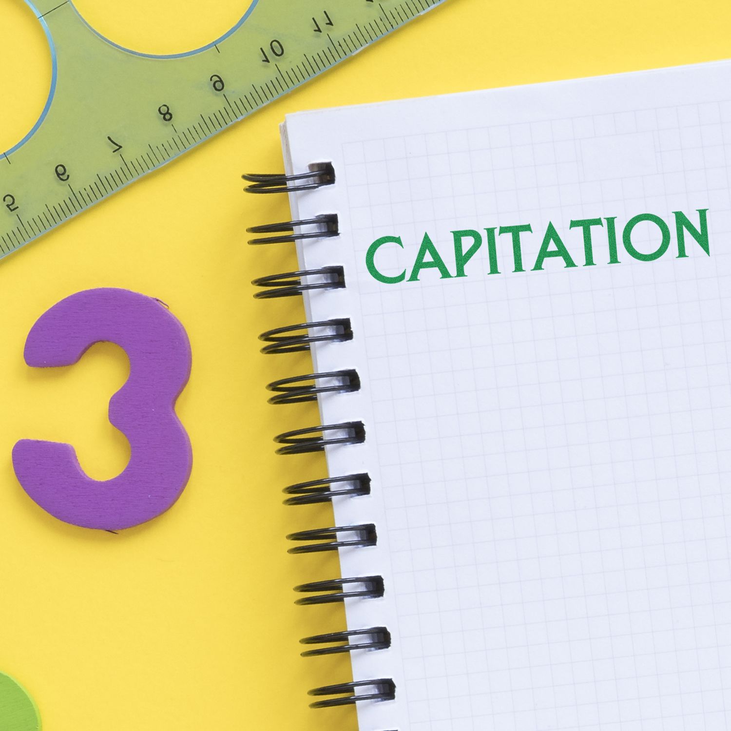 Notebook with CAPITATION text beside a ruler and question mark, representing capitation billing concept.