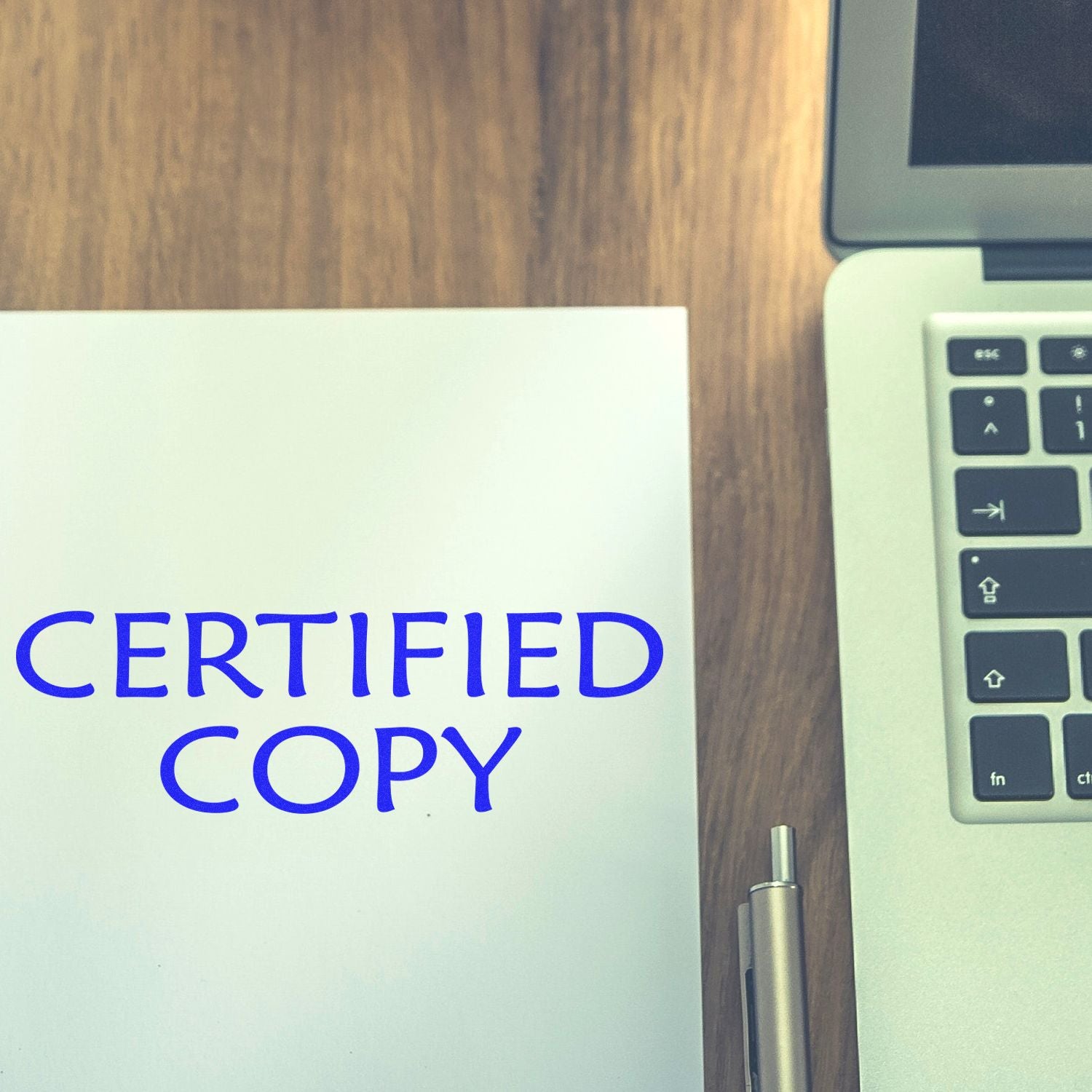 Certified copy document on desk beside laptop keyboard, used for legal paperwork, compliance and document verification.