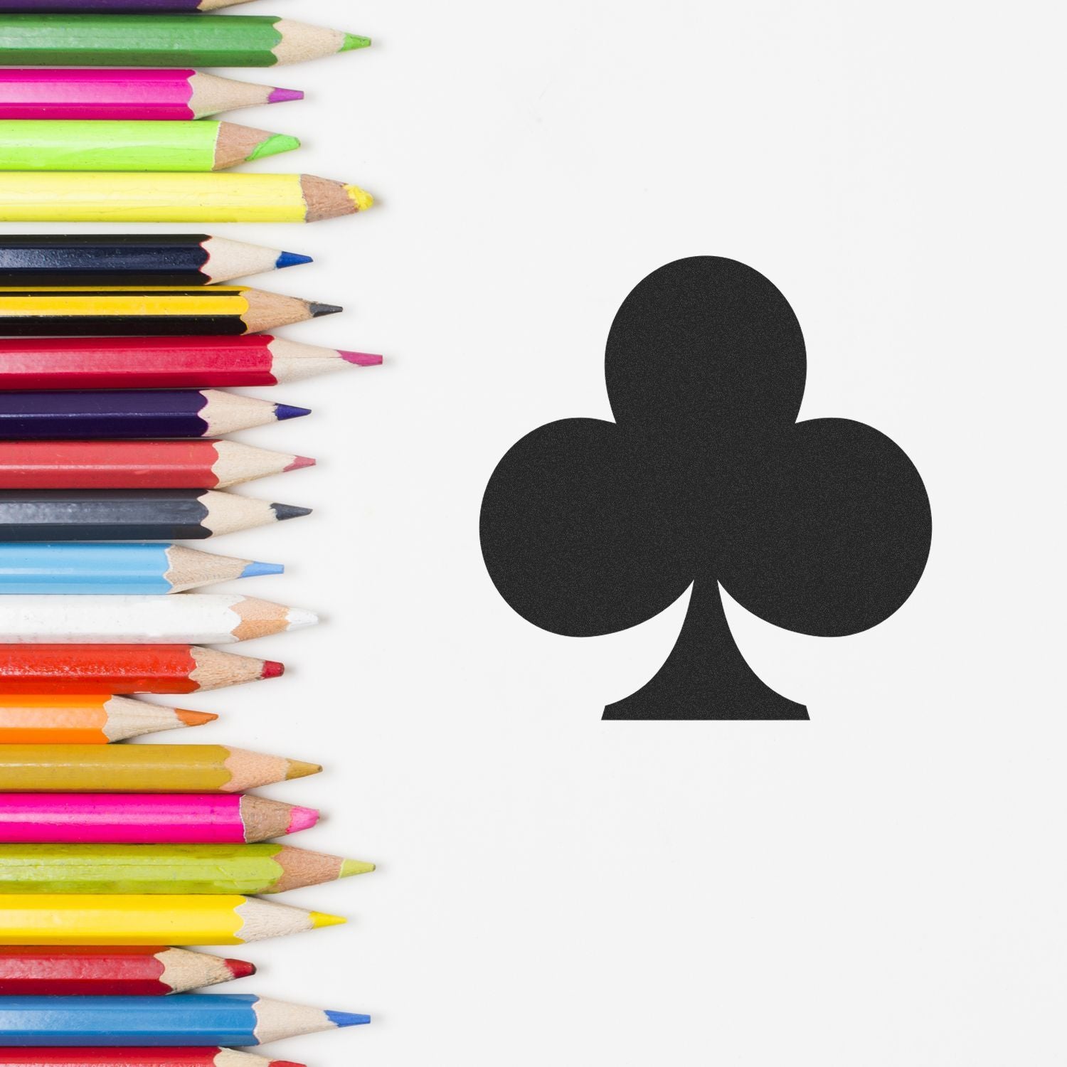 Colorful pencils arranged beside a black club suit symbol on a white background.