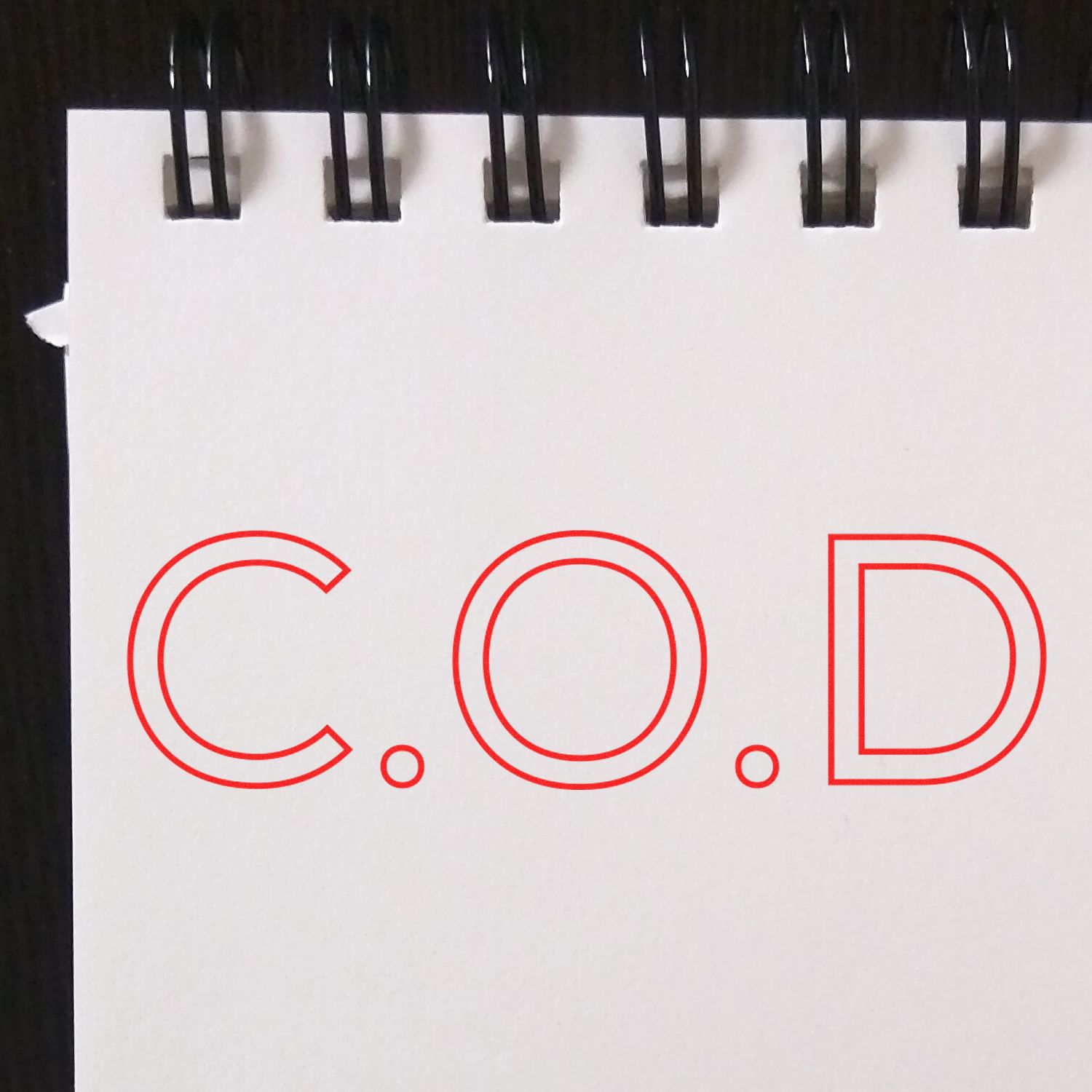 Close-up of red COD letters on a white label, identifying product shipping or status for deliveries.