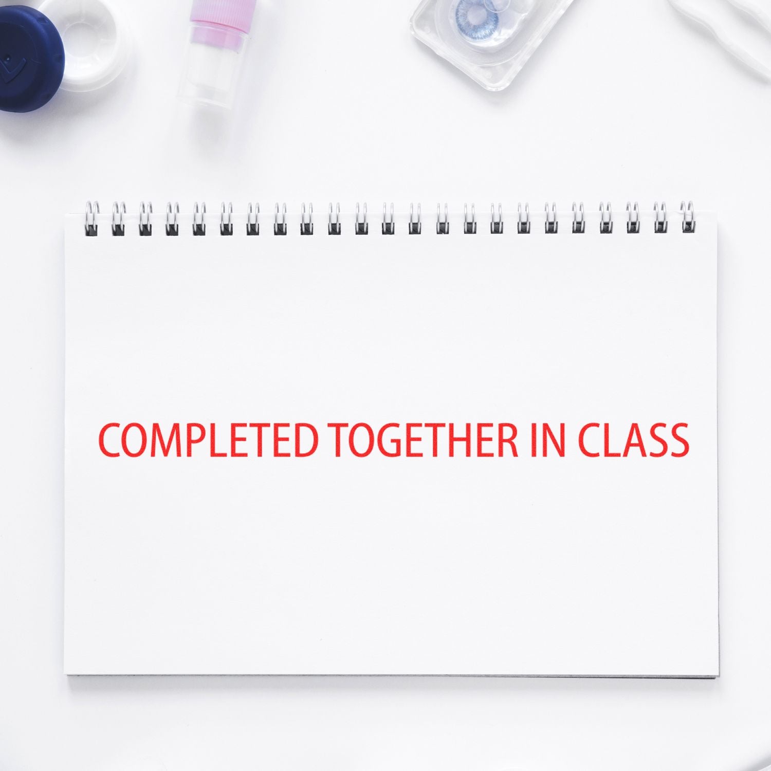 Notebook titled Completed Together in Class on desk with school supplies, highlighting classroom teamwork and learning.