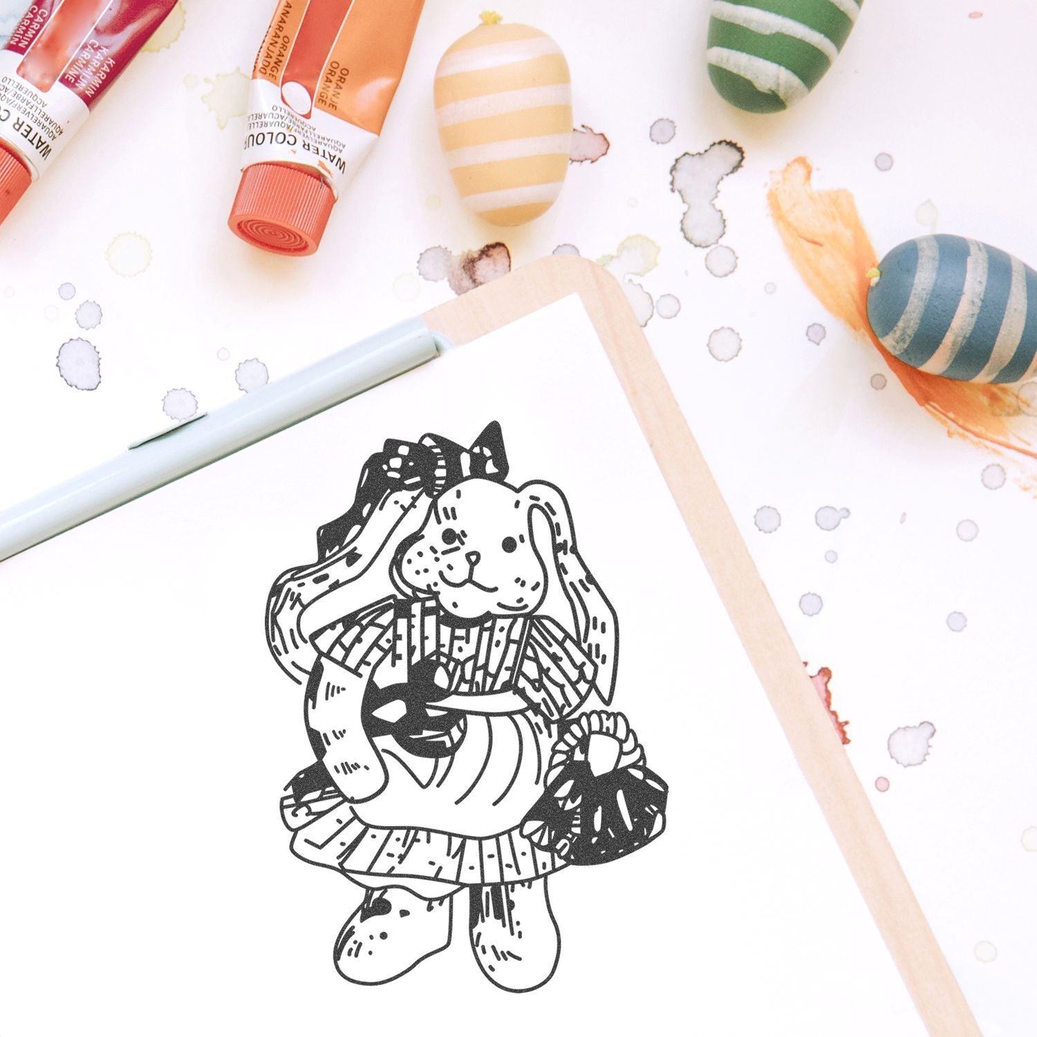 Watercolor paint tubes and abstract art supplies with a cute bunny illustration sketch on paper