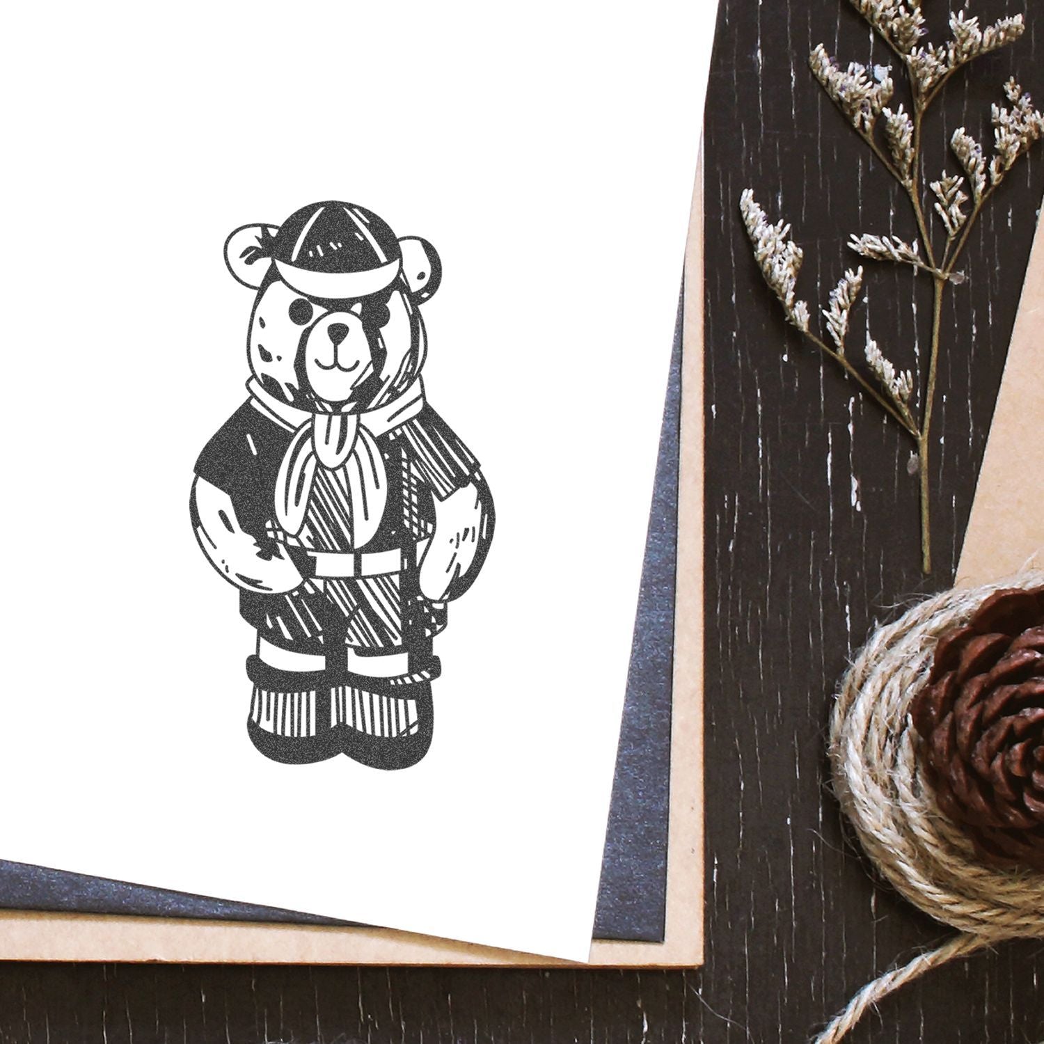 Minimalist bear illustration on blank greeting card with rustic pinecone and twine flat lay background