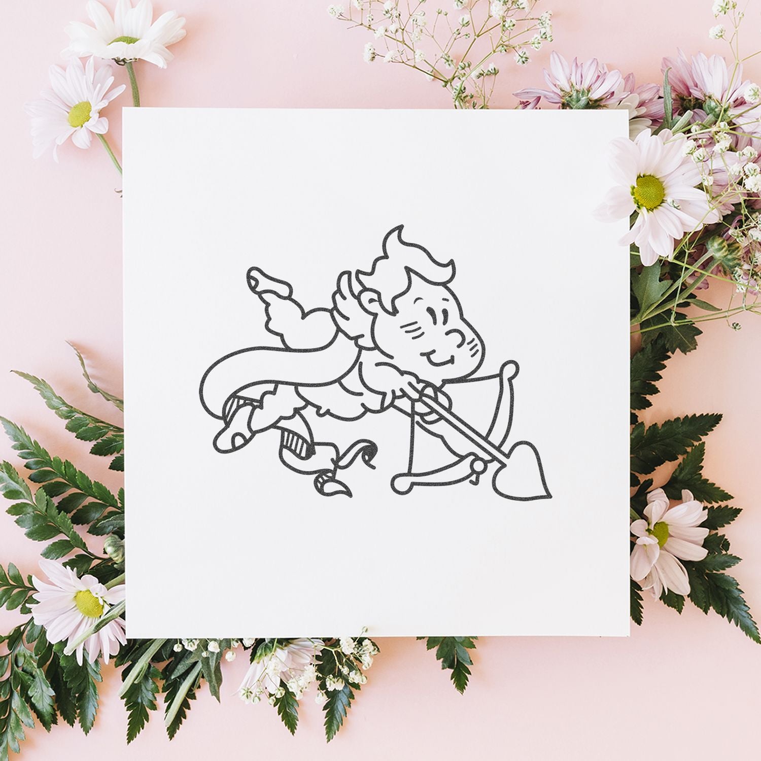 White cupid line art on a blank card surrounded by pastel pink daisies and floral arrangement on a soft pink background