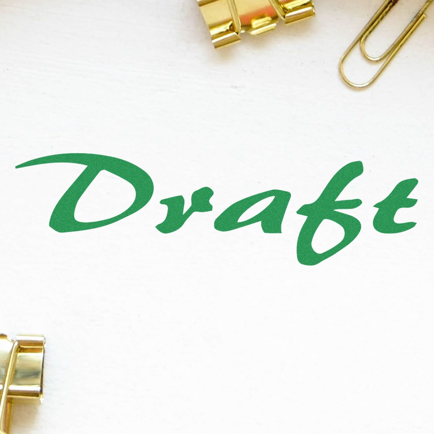 Green Draft text on white paper with gold paper clips, simple office stationery concept.