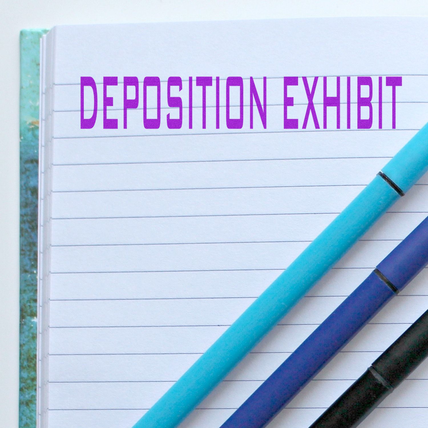 Deposition exhibit notebook with colorful pens and lined paper, legal document preparation concept
