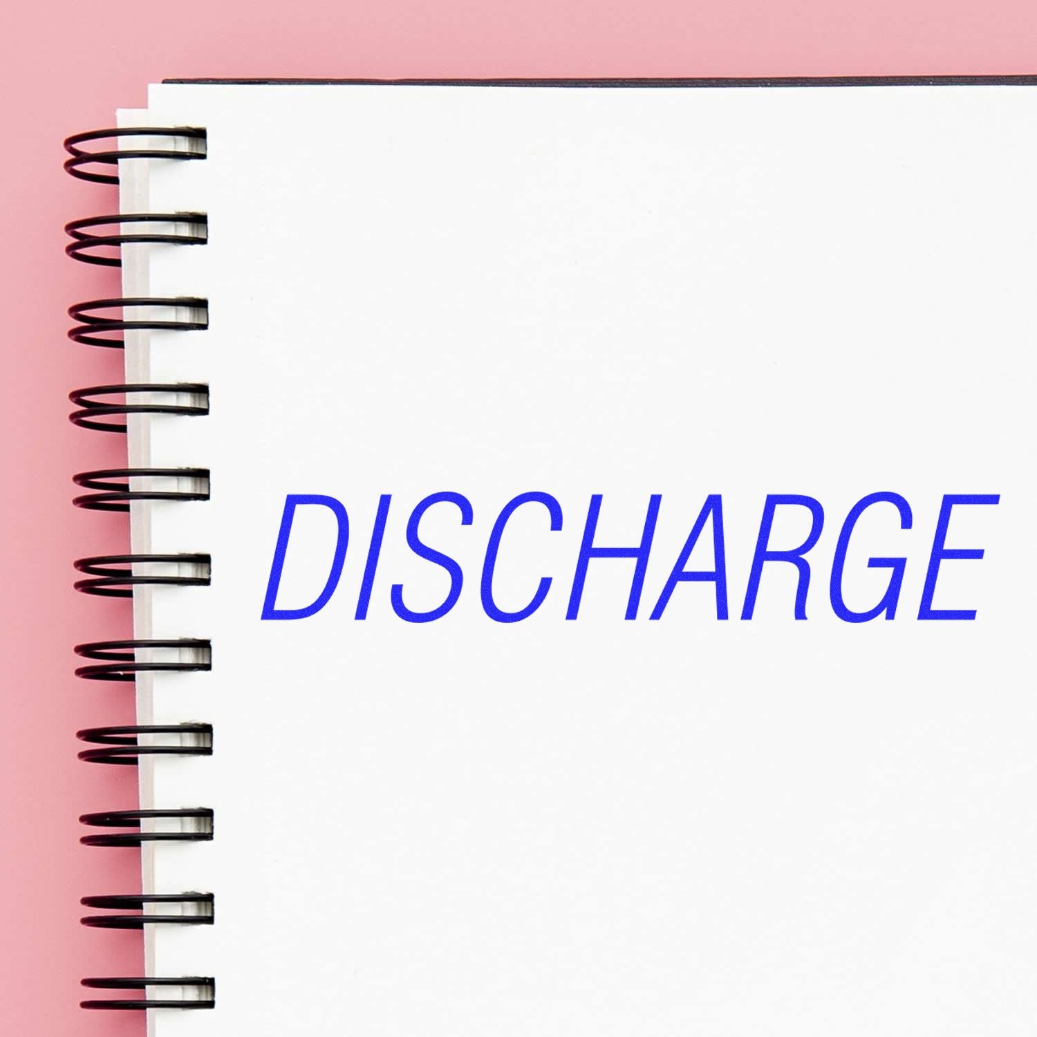 Spiral notebook with the word DISCHARGE on a white page against a pink background