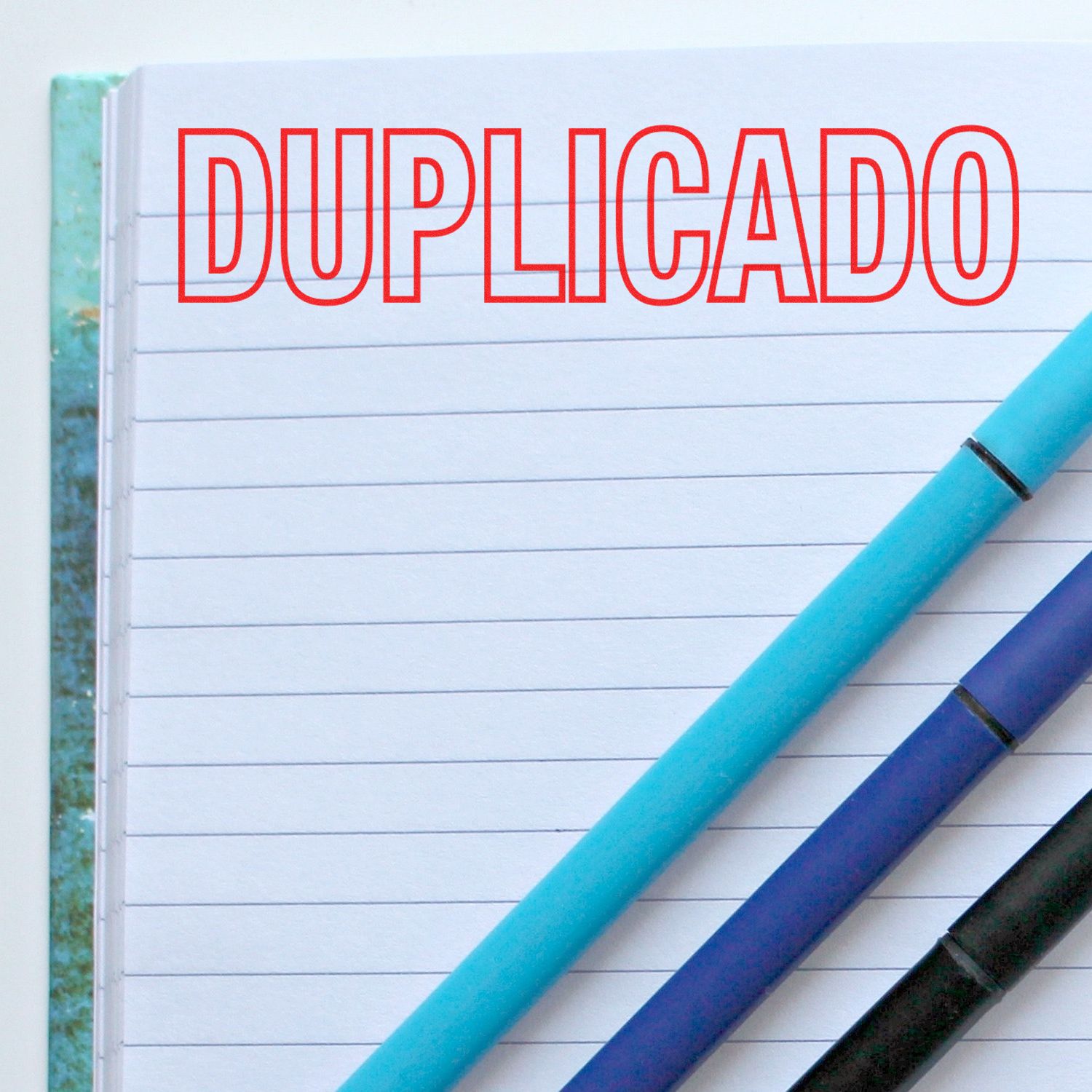 Notebook with DUPLICADO text and pens, indicating document duplication and copy printing concept