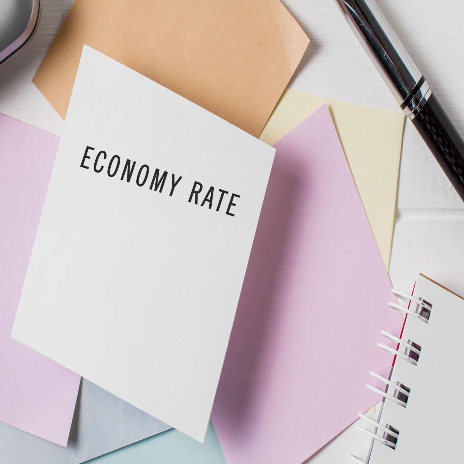 Economy rate concept on stationery notes, showing finance budgeting reminder with pen and colorful notebooks for low-cost travel planning.