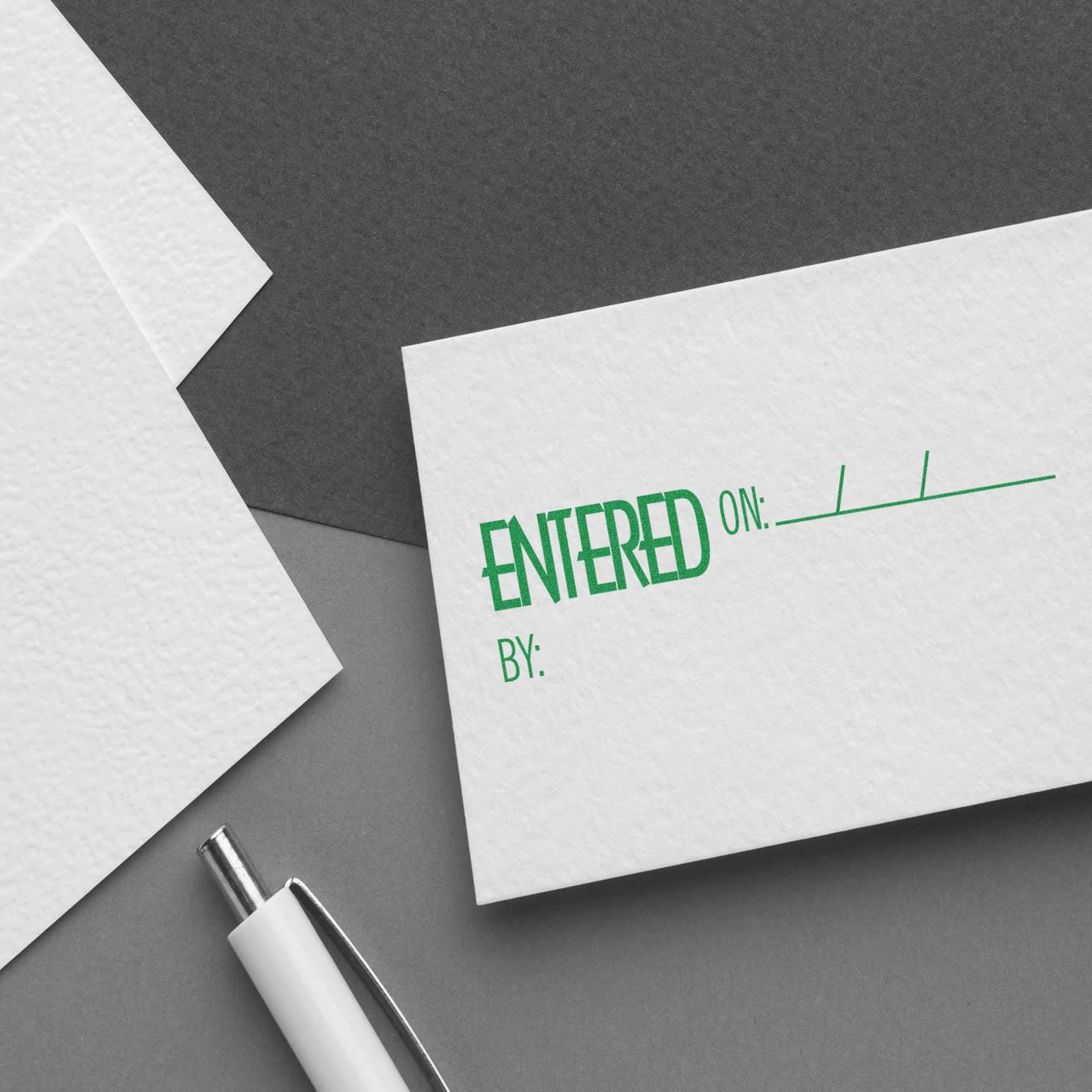 Close-up of a stamped envelope and form with ENTERED ON and BY text beside a pen.