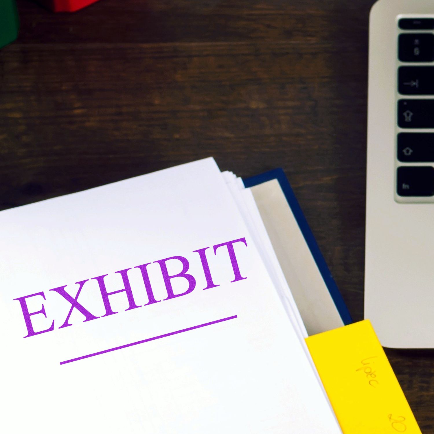 Exhibit document labeled EXHIBIT on desk with laptop keyboard, supporting legal case or business presentation.