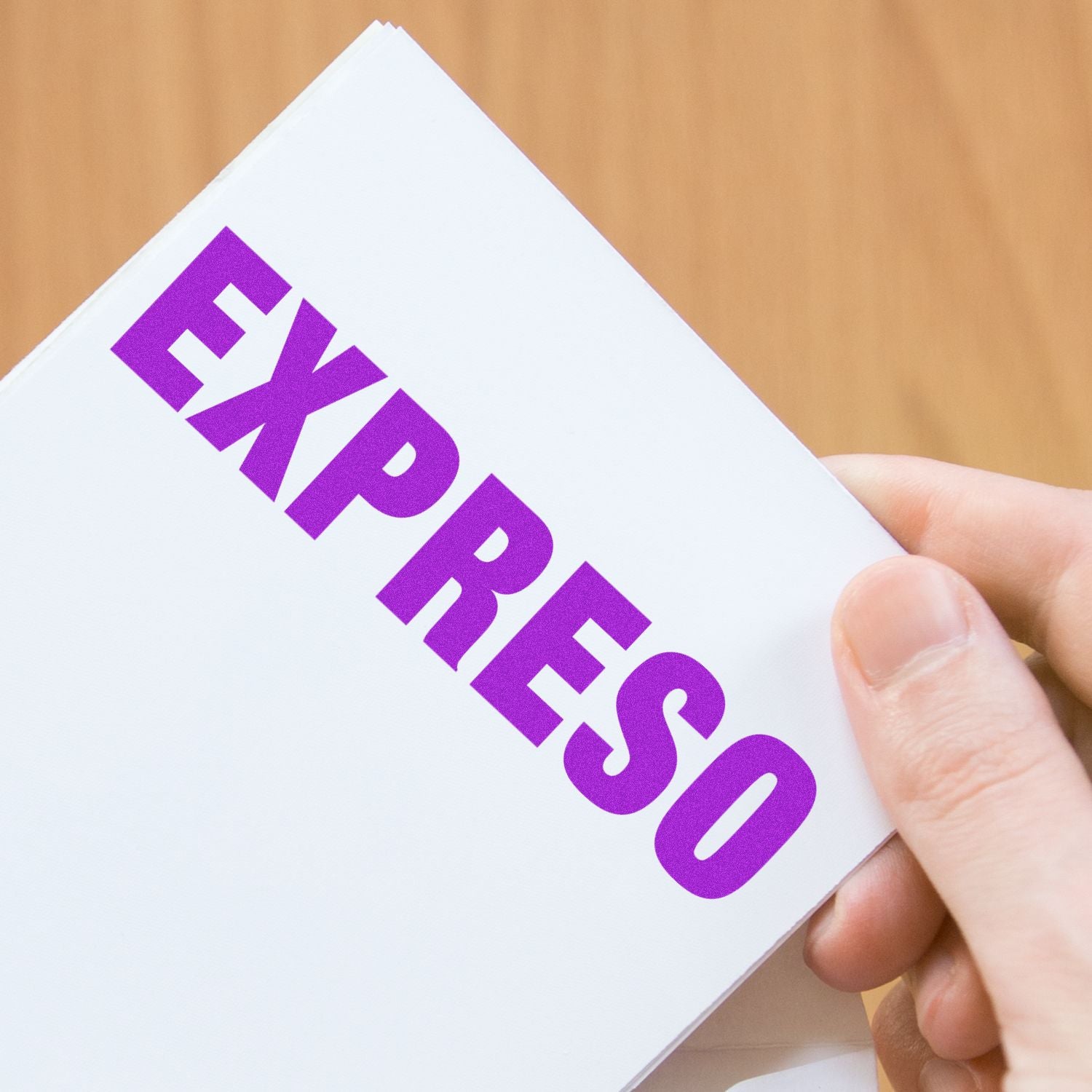 Close-up of a hand holding a white business card with bold purple typography, showcasing branding for marketing or promotions.