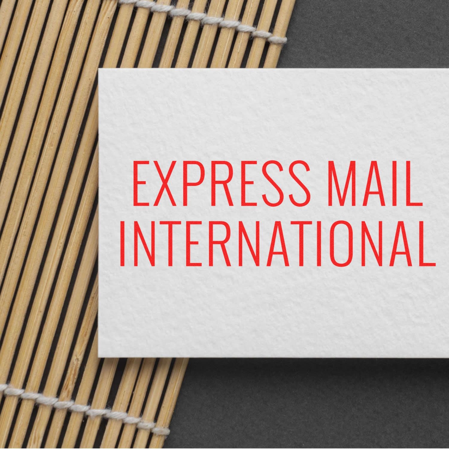 Express Mail International shipping label on a white card over a bamboo placemat, indicating fast international delivery service.