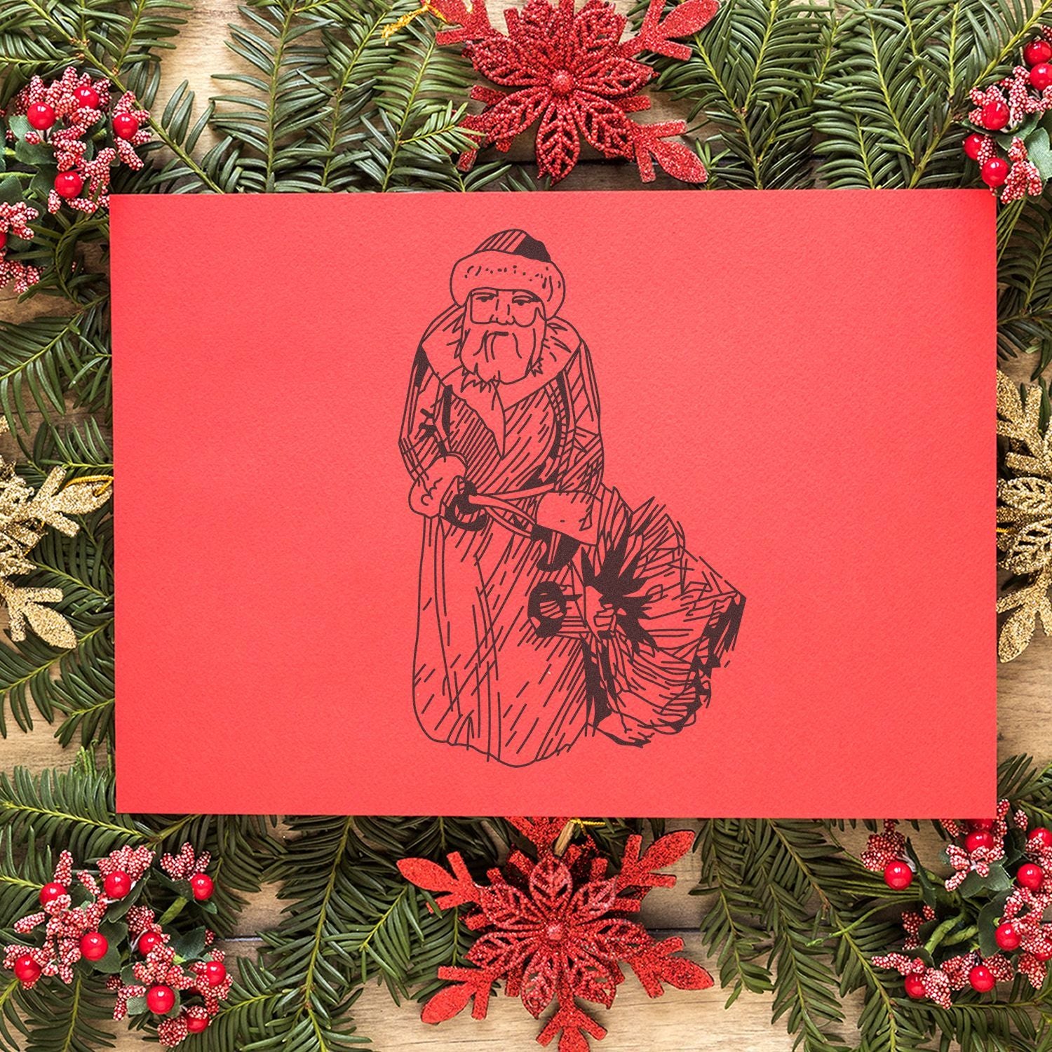 Festive Christmas card with Santa illustration on red paper surrounded by evergreen wreath and red holiday decorations.