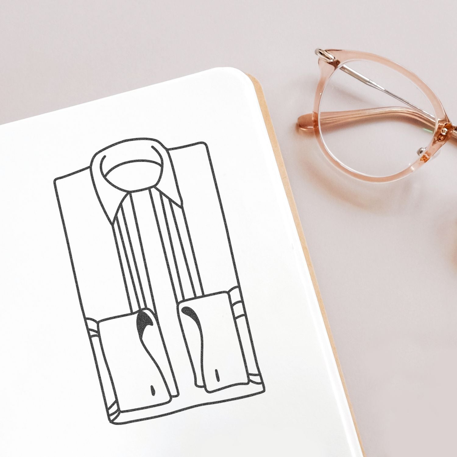 Fashion sketch in a notebook with eyeglasses on a white desk, minimalist office workspace.