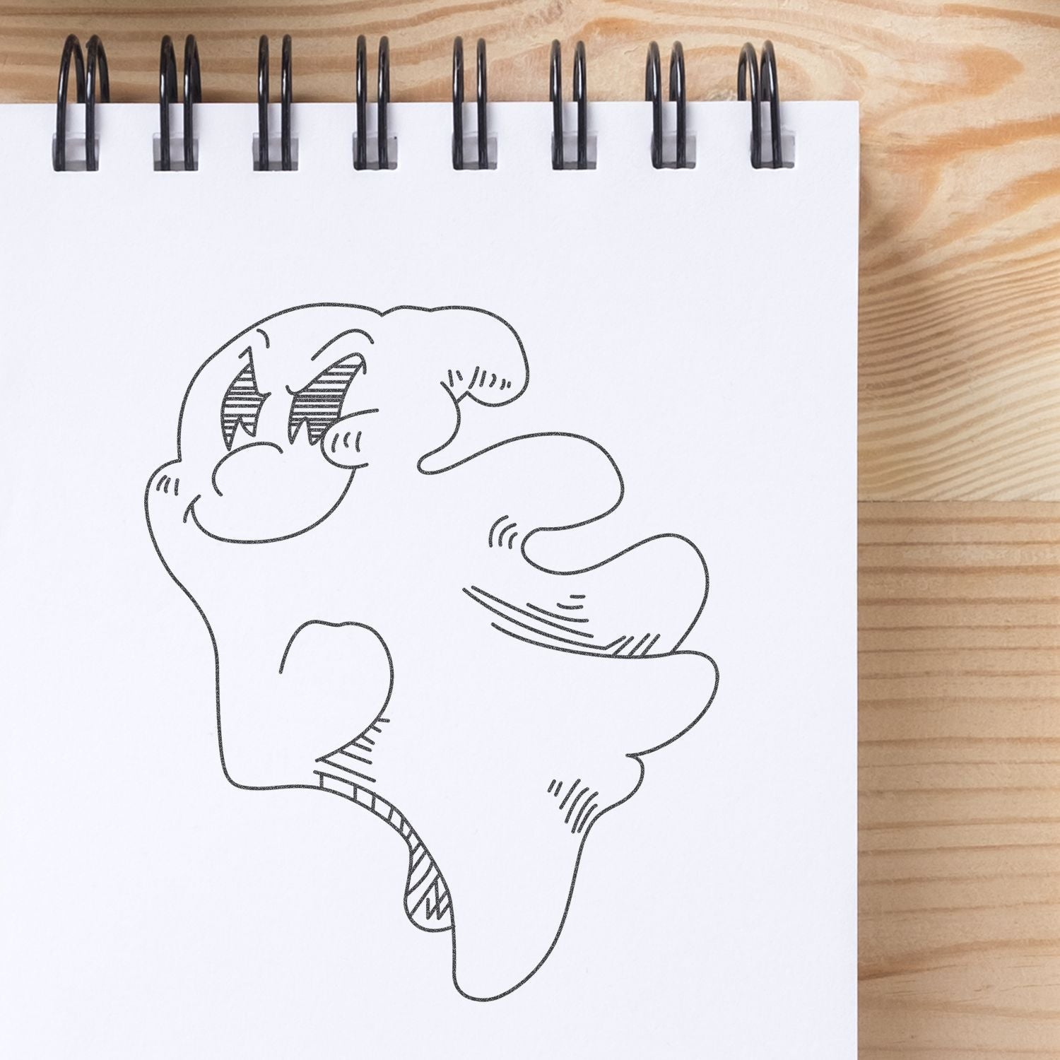 Spiral notebook with abstract hand-drawn cartoon doodle sketch on a wooden desk