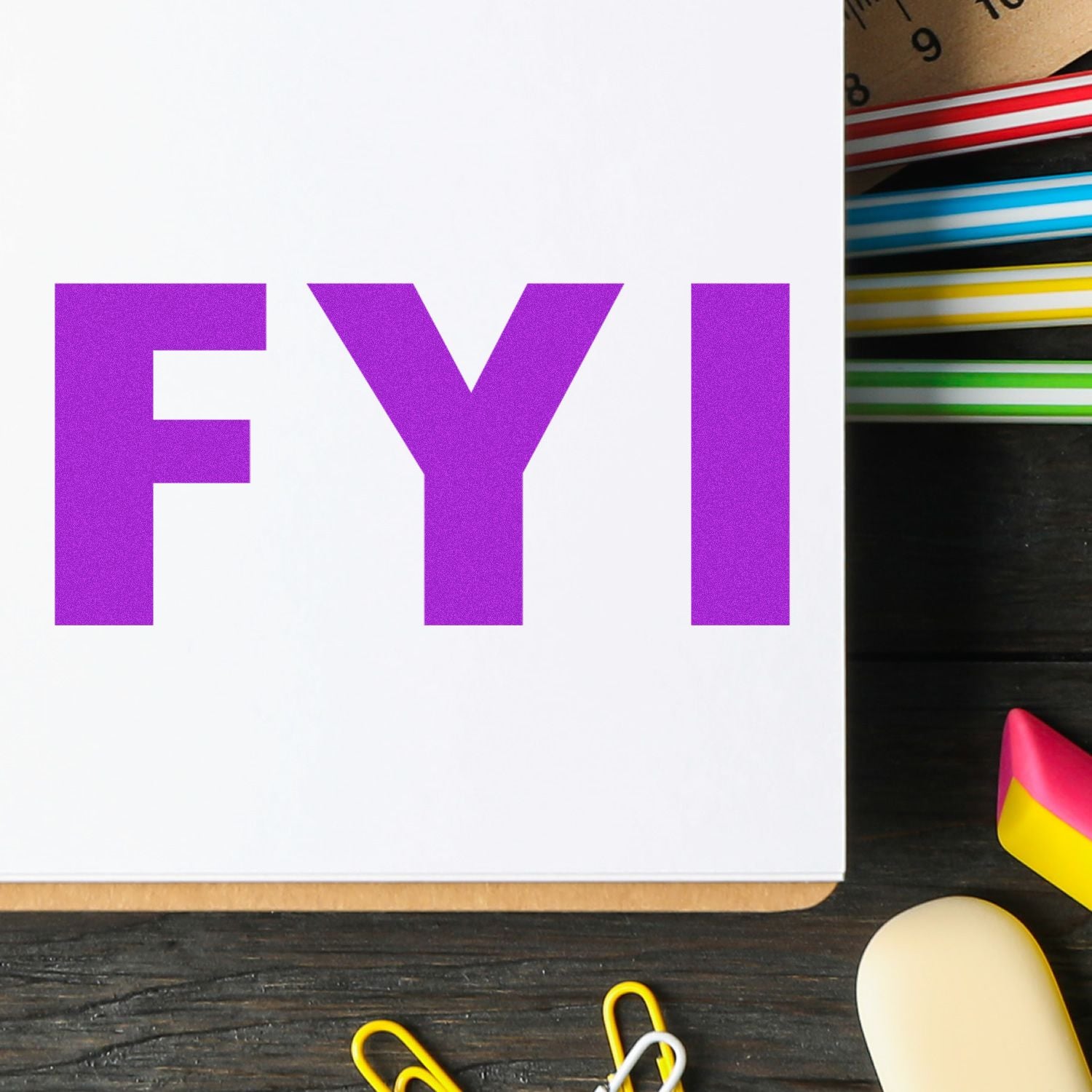 Purple FYI letters on a desk of stationery, visual for sharing important information updates or announcements