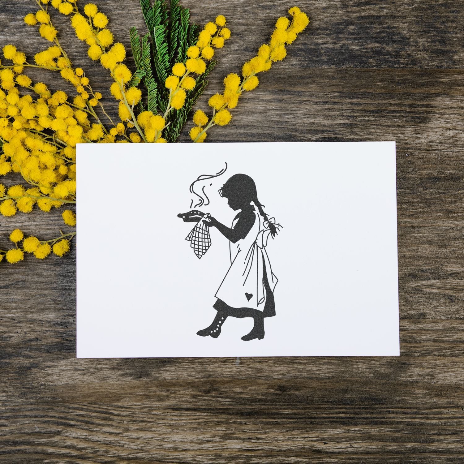 Black and white girl silhouette greeting card with yellow mimosa flowers on a rustic wooden table.