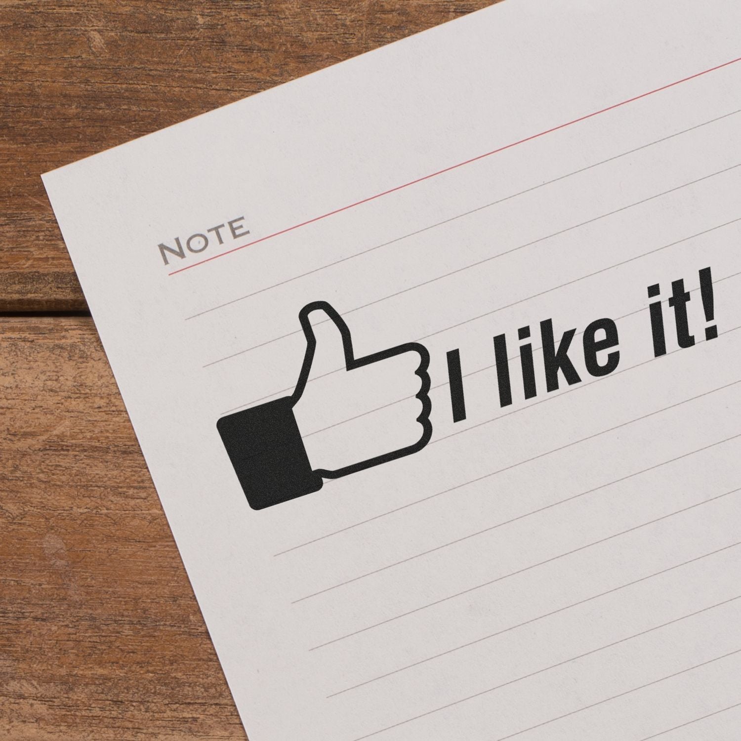 Thumbs up icon on a note paper with I like it! text on a wooden desk, symbolizing positive feedback and approval.