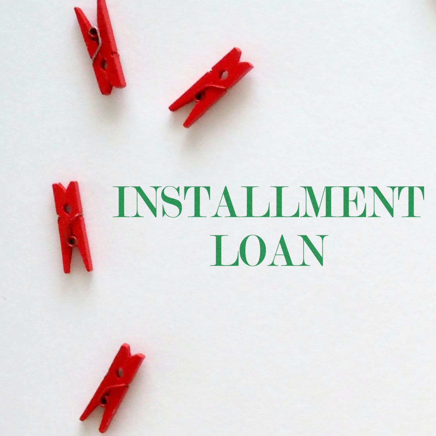 Red clothespins on white background with text INSTALLMENT LOAN, highlighting installment payment financing.