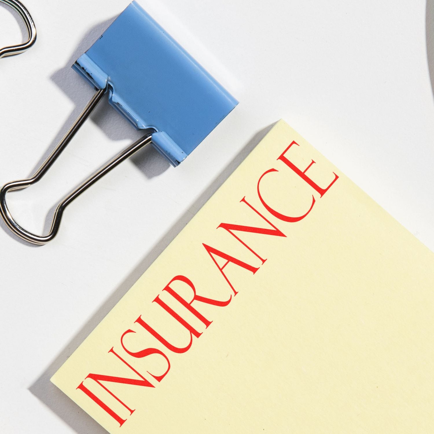 Blue binder clip securing a printed document with red lettering, symbolizing document organization and filing.