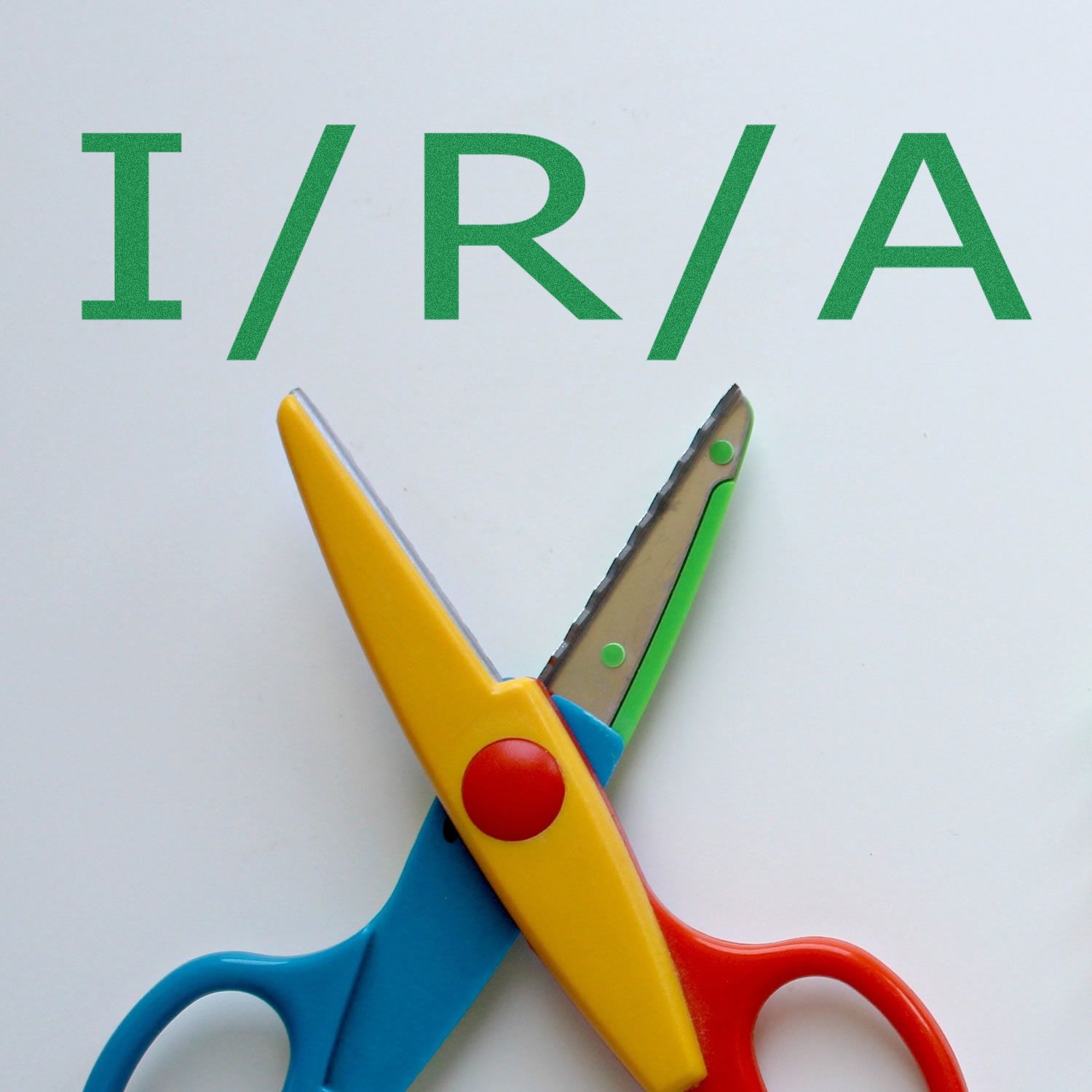 Colorful scissors cutting paper above green IRIA letters, illustrating a DIY crafting or education safety concept.