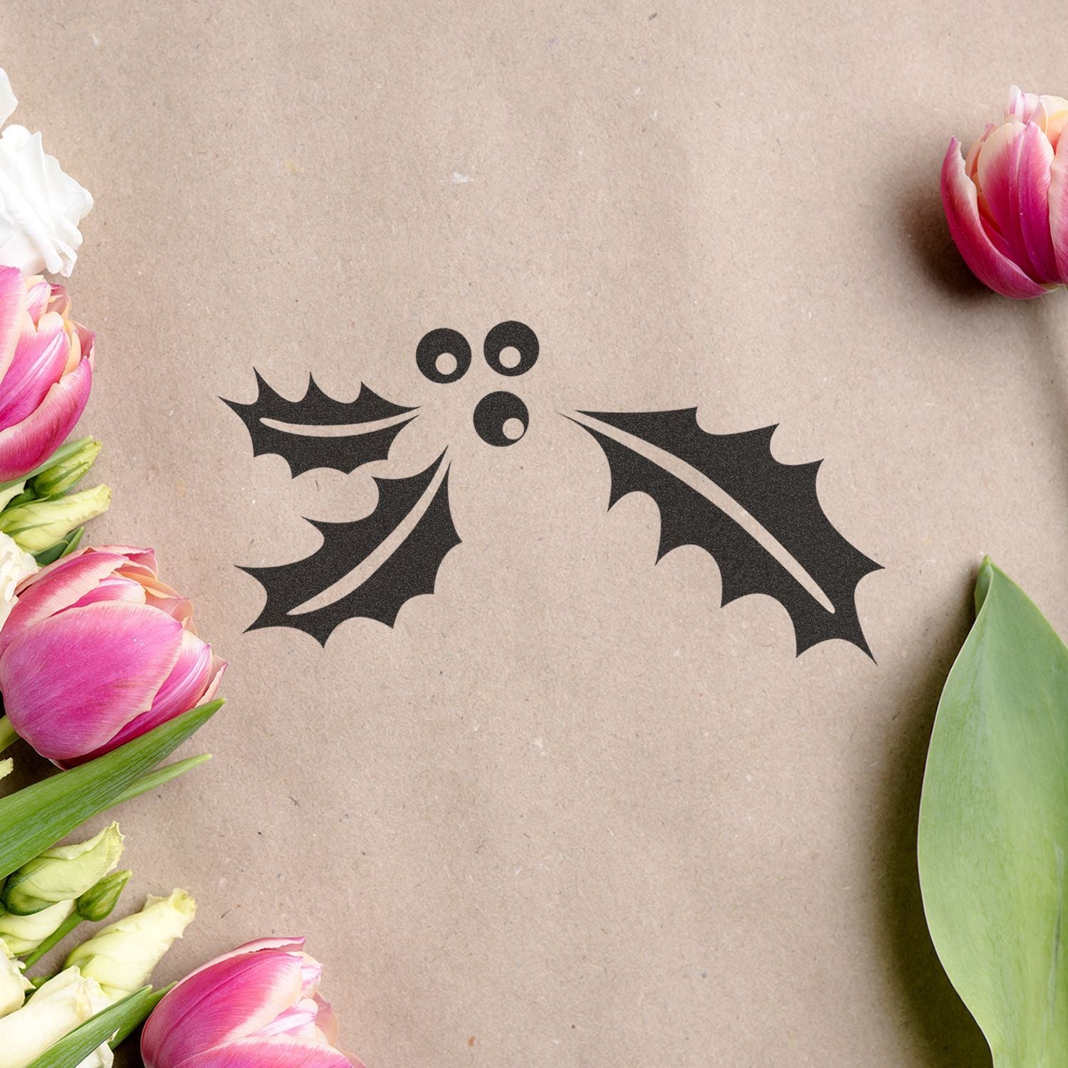 Pink tulips framing a black holly berry icon on a kraft paper background