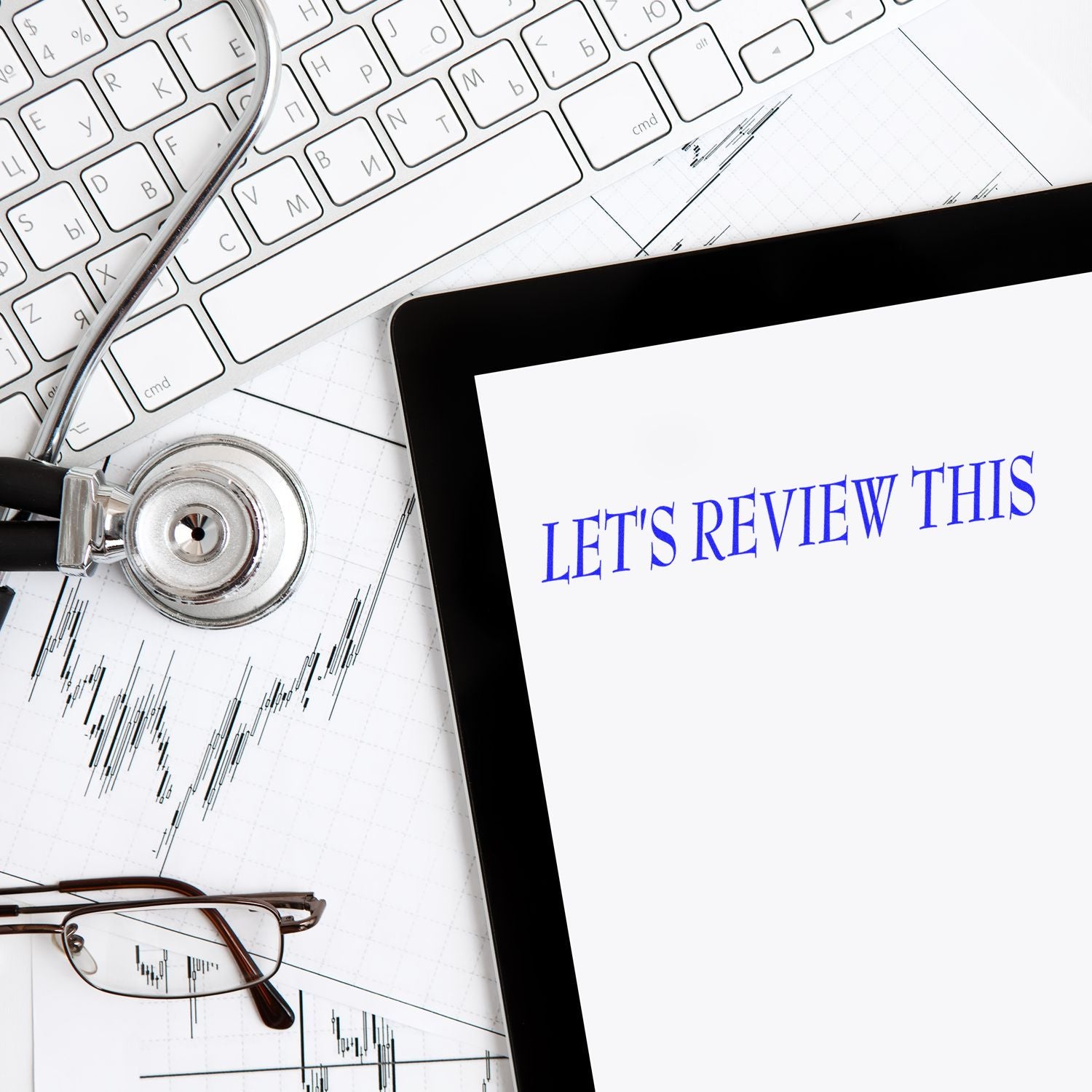 Stock market data analysis concept: trading charts and financial report review with stethoscope, glasses, keyboard, and 'Lets review this'.