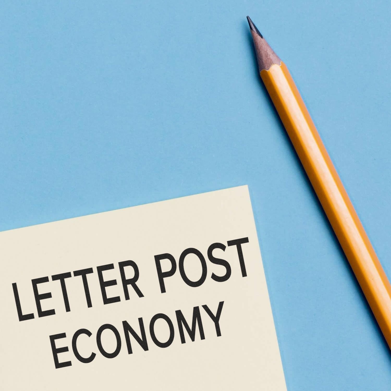 Economy letter post shipping concept: pencil beside a postal note reading Letter Post and Economy on a blue background.