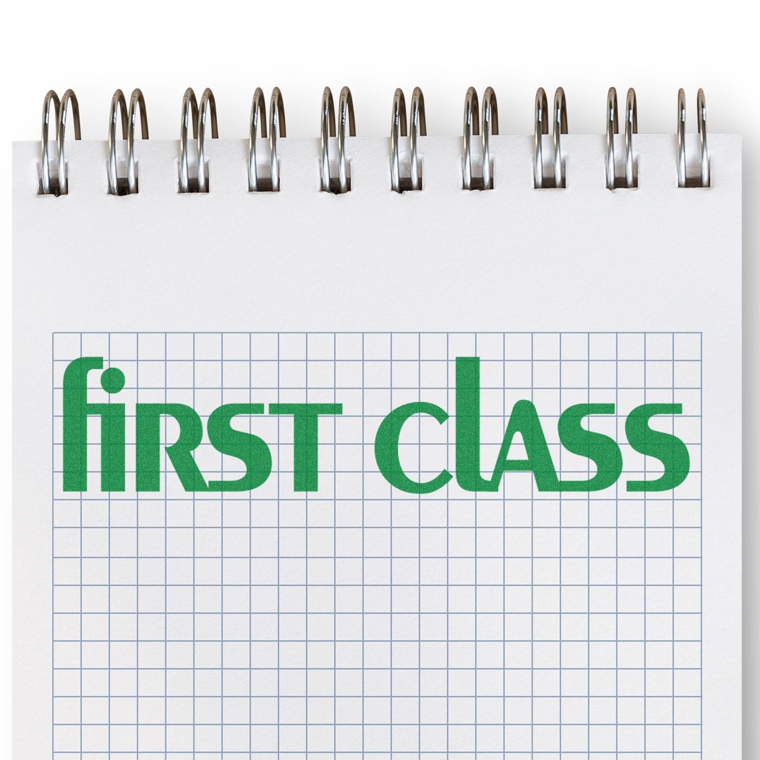 Notebook page with green first class text on spiral-bound graph paper, education and stationery concept