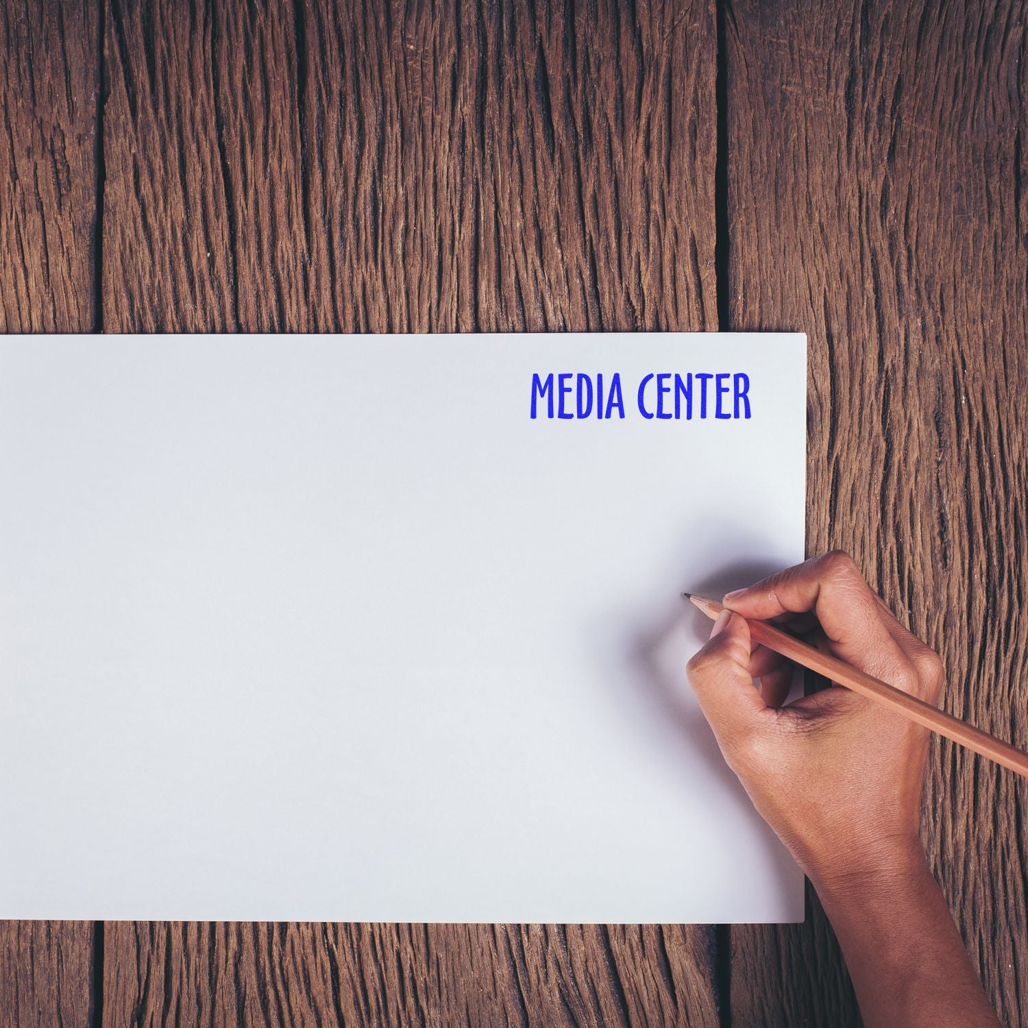 Hand writing on blank page labeled MEDIA CENTER over wood desk, illustrating media content marketing for branding communication.