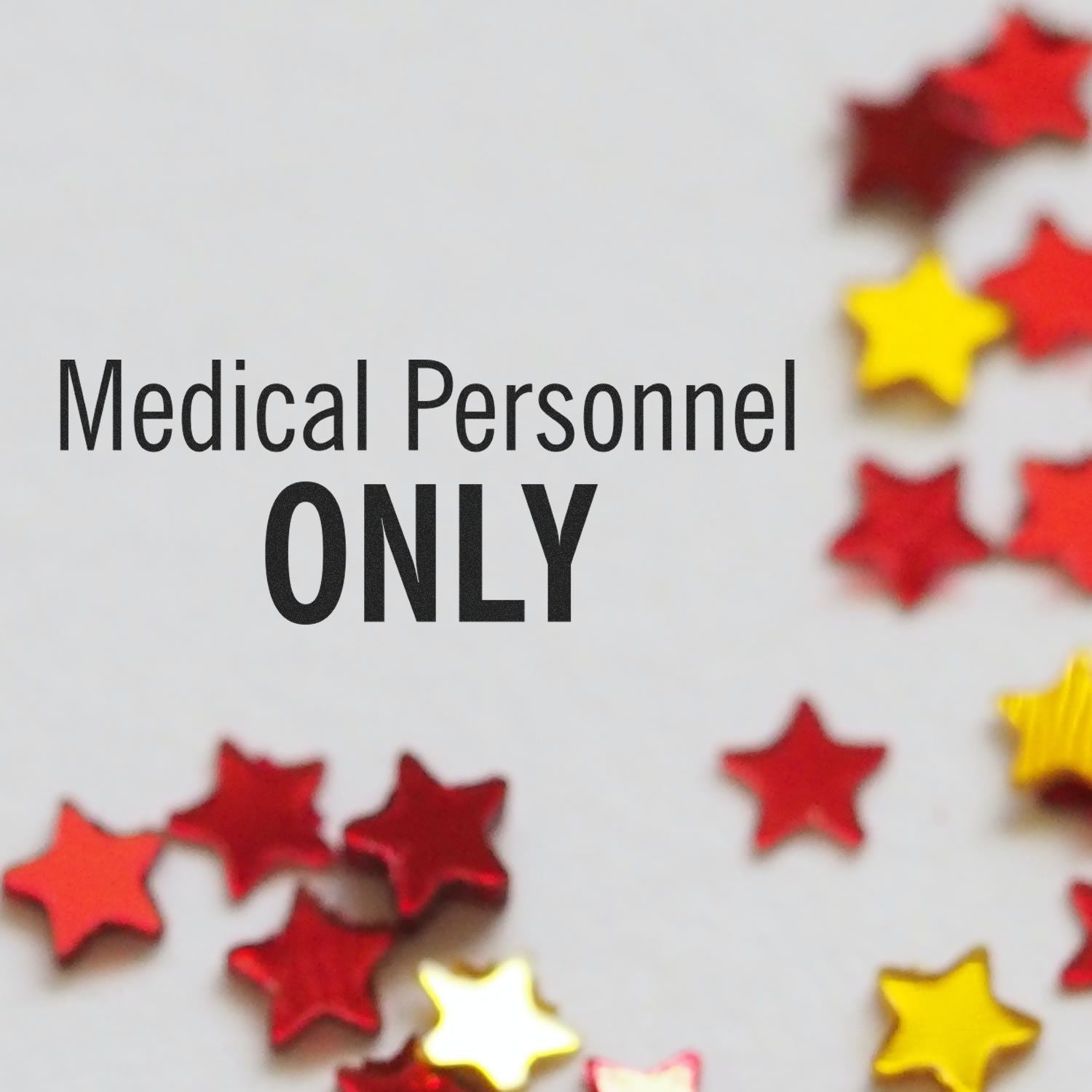 Medical personnel only sign with red and yellow star decorations on a white background.