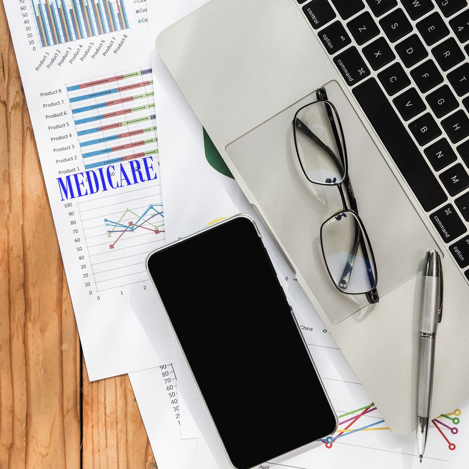 Healthcare analytics desk setup with medical chart reports, stethoscope, laptop keyboard, and phonedata-driven medical planning.