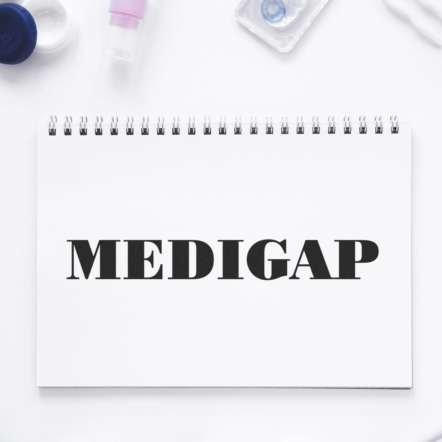 Medical gap health planner notebook labeled MEDIGAP on white desk with prescription bottles and vaccine vials for healthcare branding