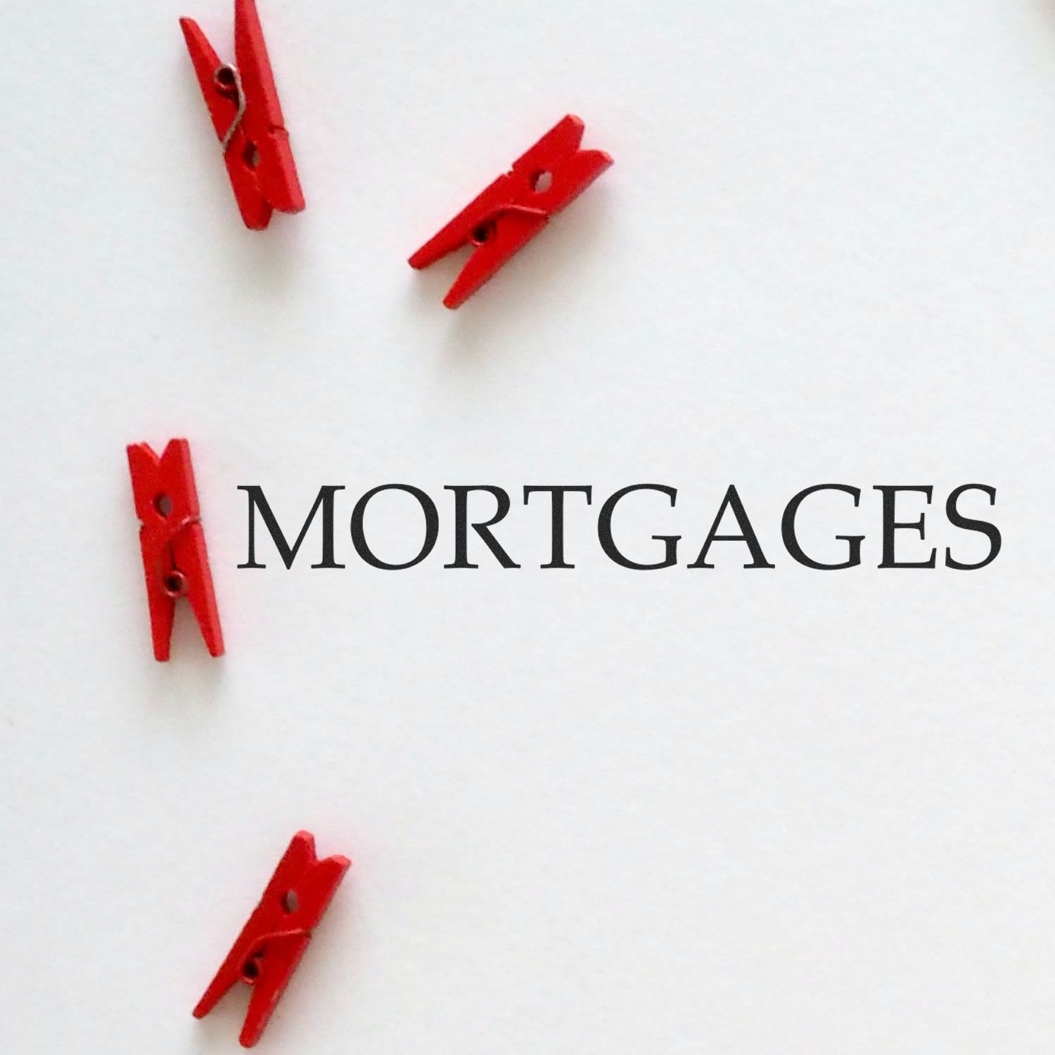 Mortgage concept image with red clothespins holding documents and the text MORTGAGES on a white background for SEO.