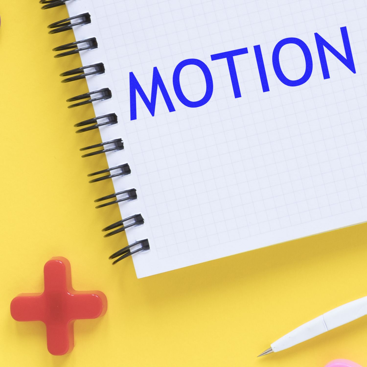 Notebook page reading MOTION with pencils and red cross on yellow background, illustrating physics motion learning.