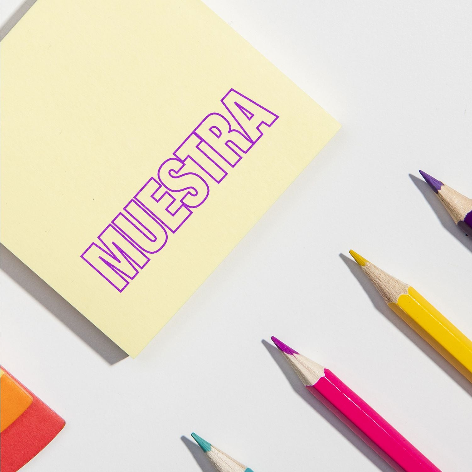 Yellow sticky note with bold purple word IDEA and colored pencils on white background, representing creative brainstorming and planning ideas
