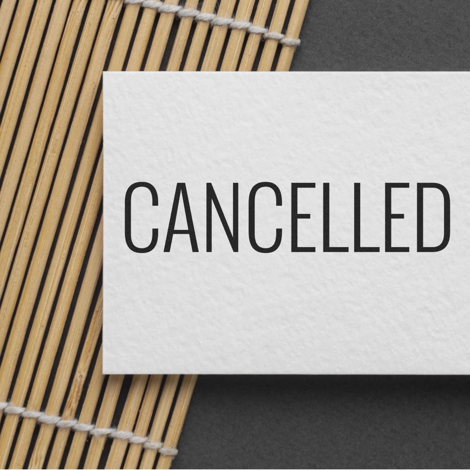 Cancelled notice card reading CANCELLED on a woven bamboo placemat, communicating an event or service cancellation message clearly.