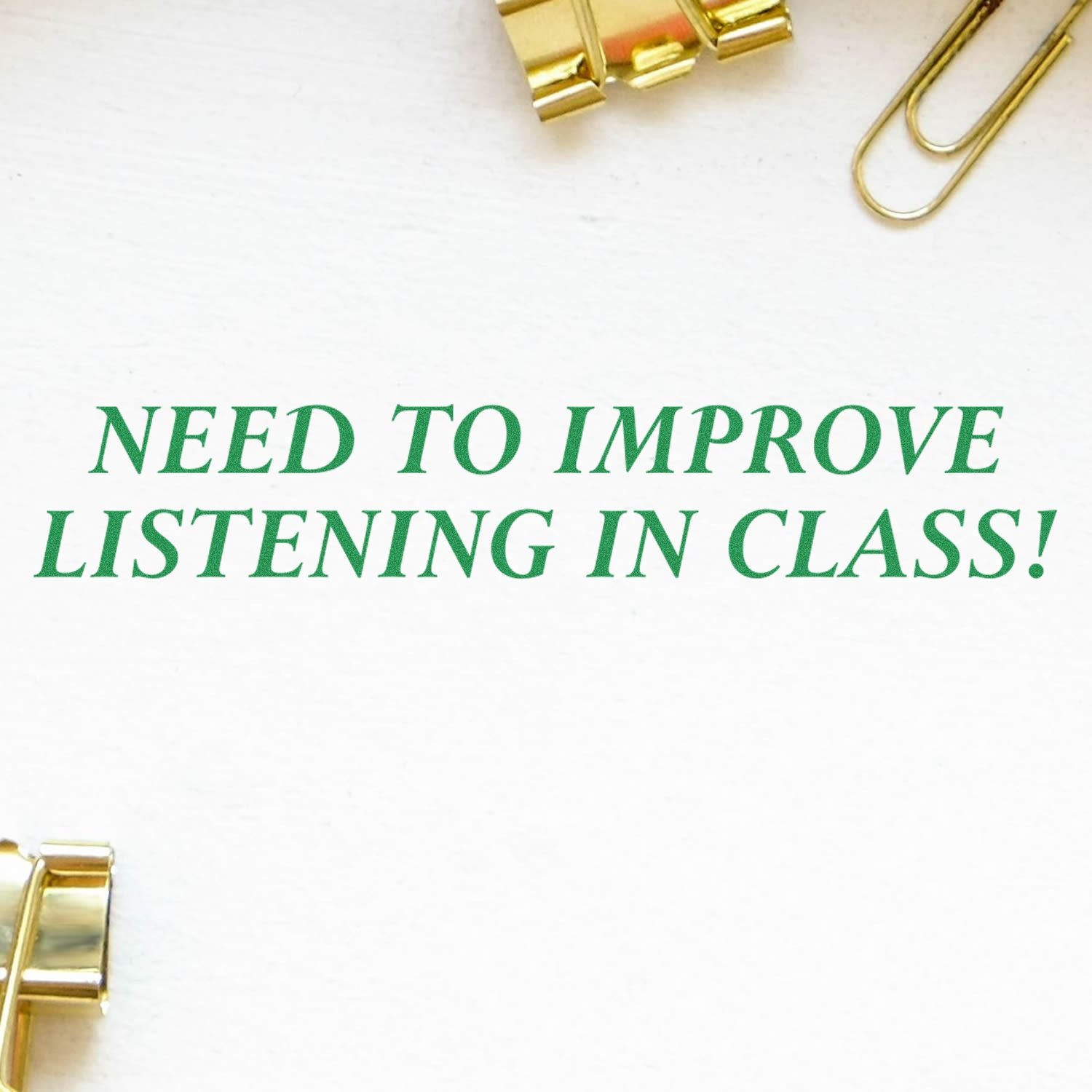 Green text reading Need to improve listening in class! on a white background with gold paper clips.