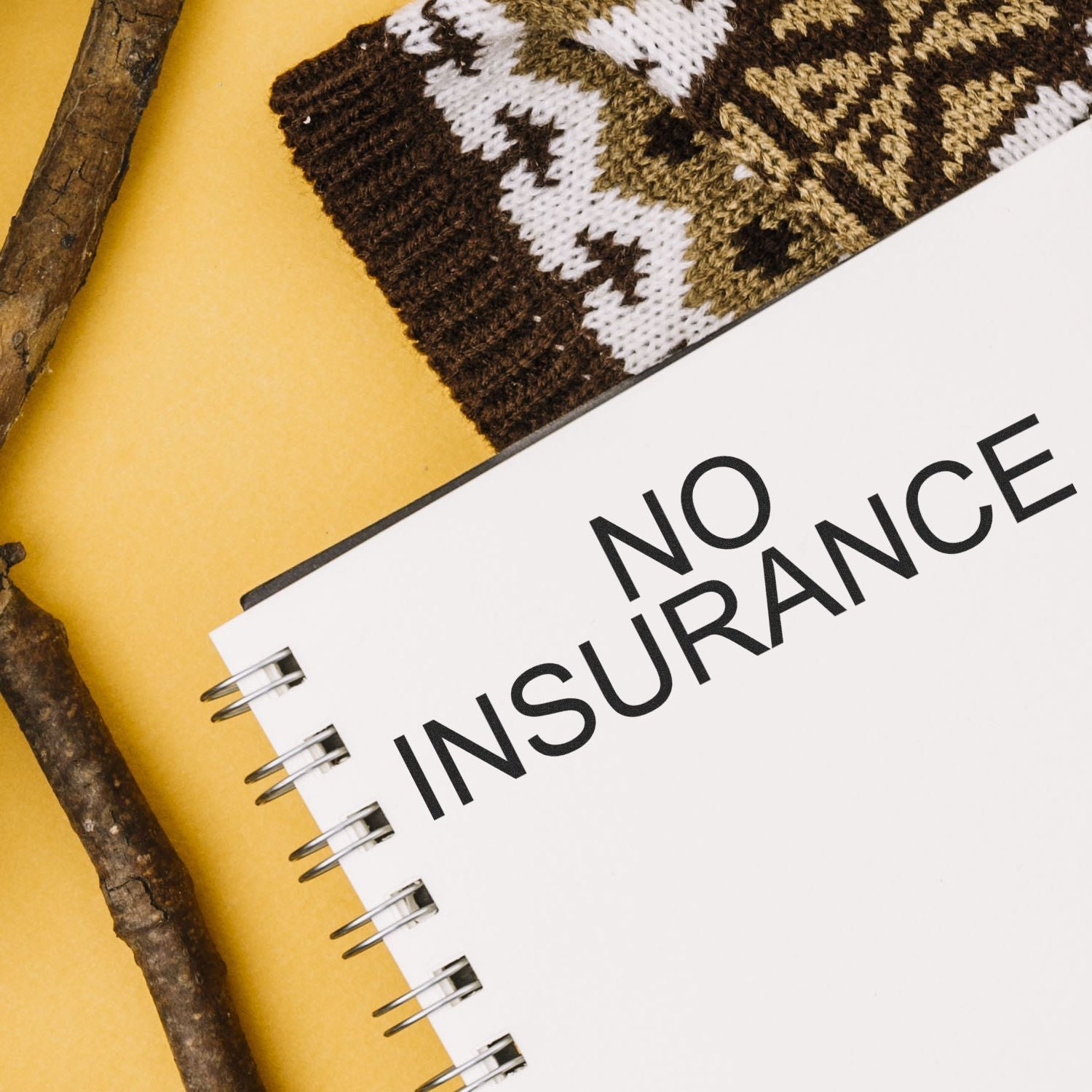 No insurance concept: close-up notebook with bold NO INSURANCE text and knitted fabric background, promoting insurance awareness.