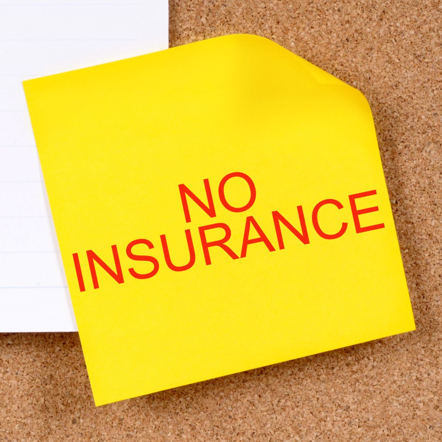 No insurance message on yellow sticky note pinned to a cork board, emphasizing need for health coverage.